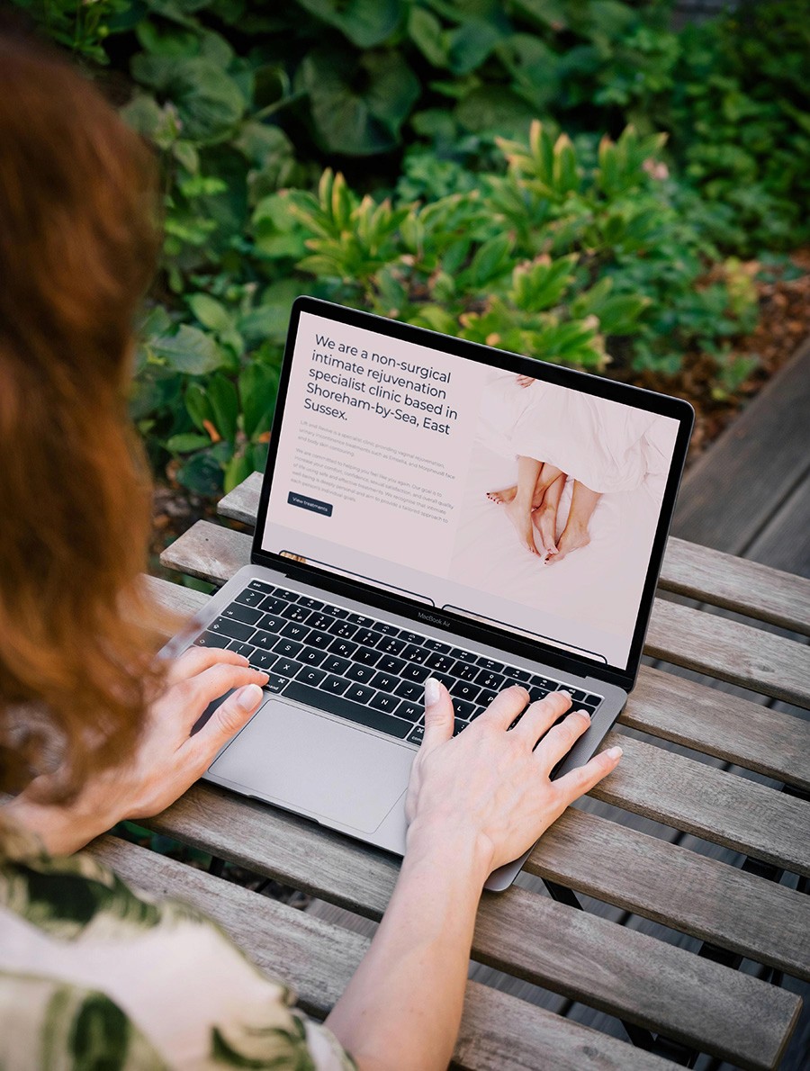 woman outside at a garden table viewing the lift and revive website on her laptop