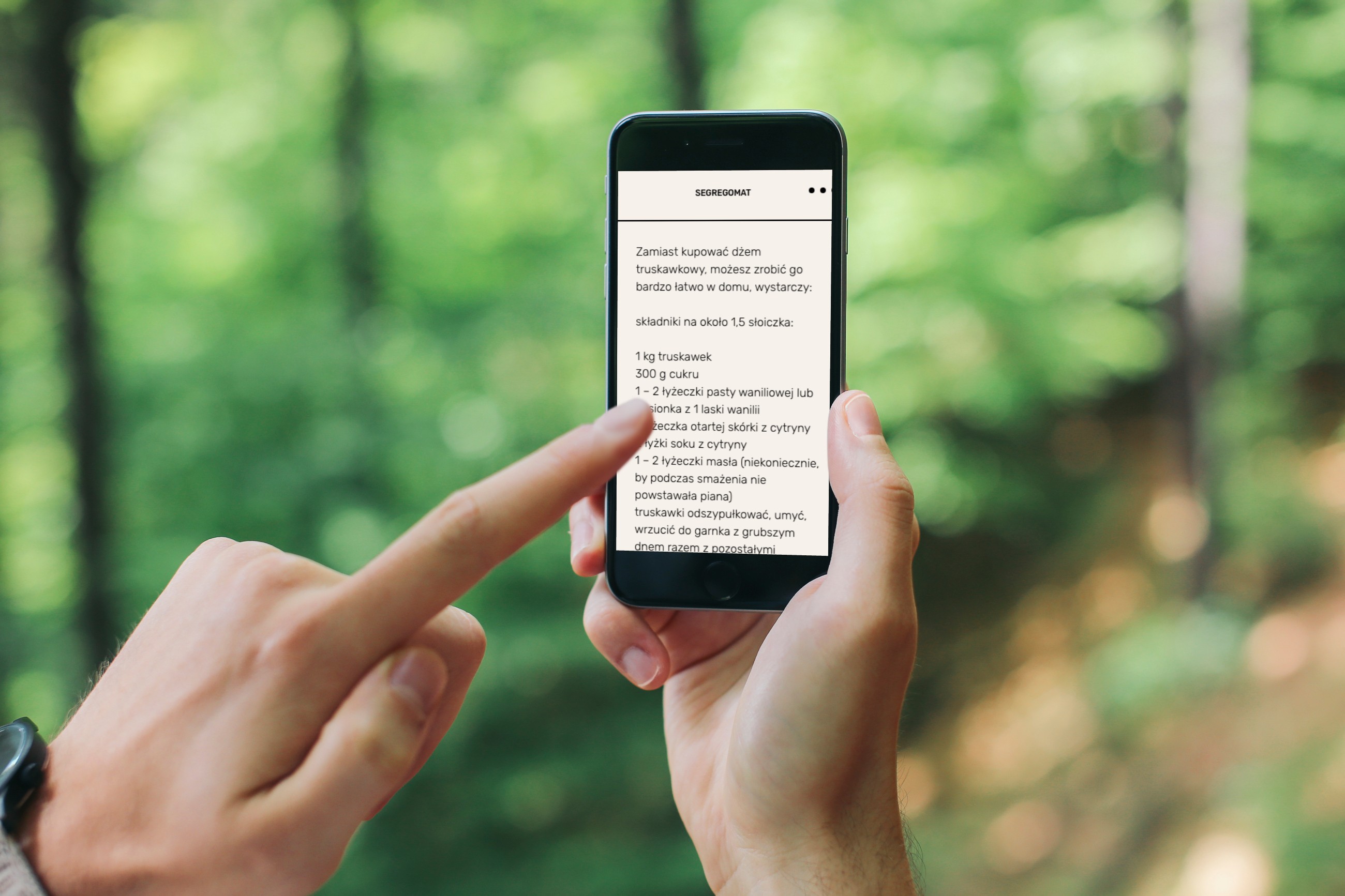 An image featuring a person pointing at an iPhone 6 screen in a forest setting.