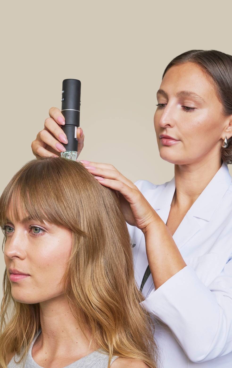 A hair care professional applying a treatment to a client's scalp in a salon setting.