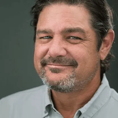 Portrait of a smiling man with salt-and-pepper beard and mustache.