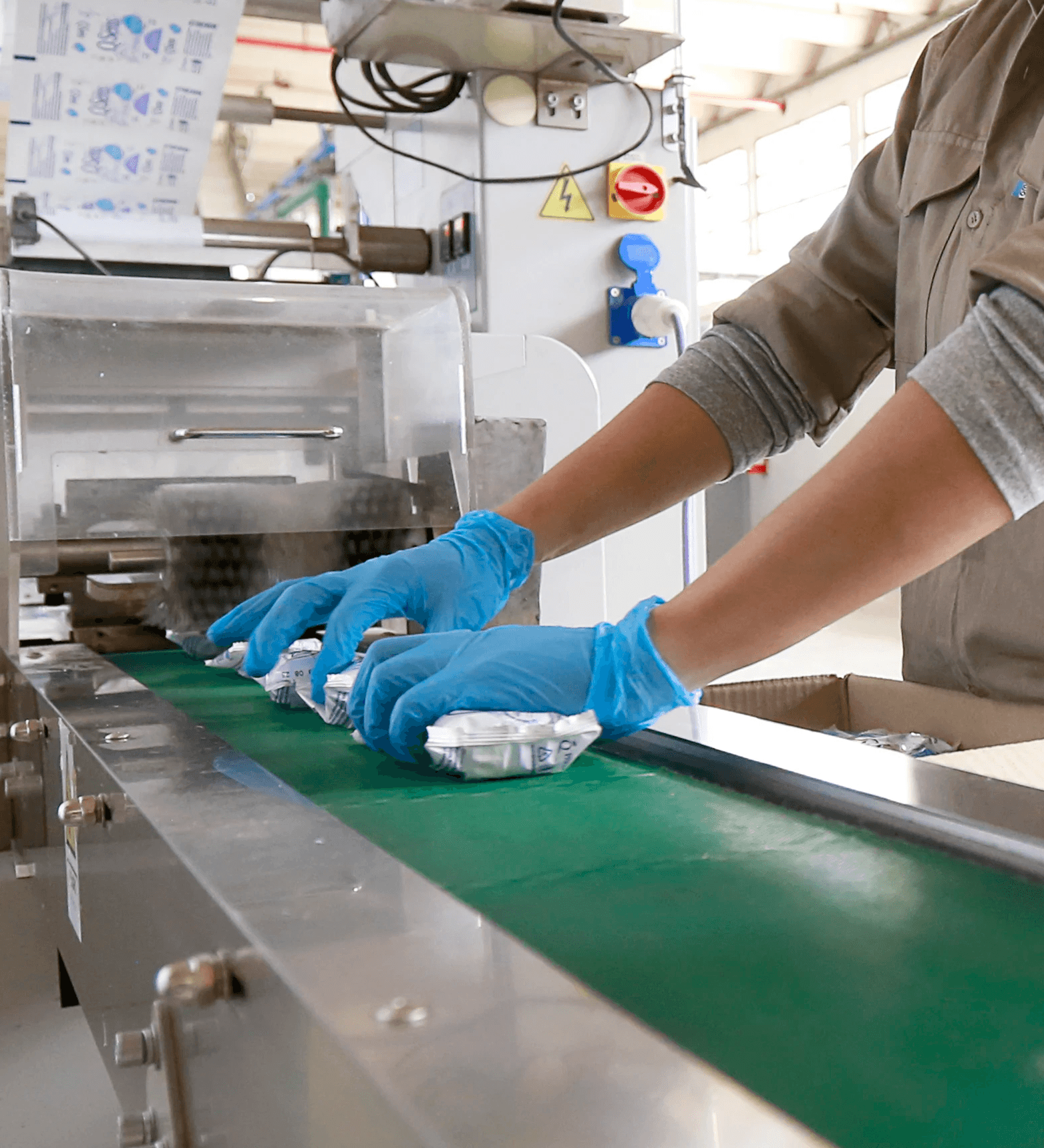 Operario con guantes trabajando en línea de producción de jabones y grasas PQL, garantizando higiene y calidad.