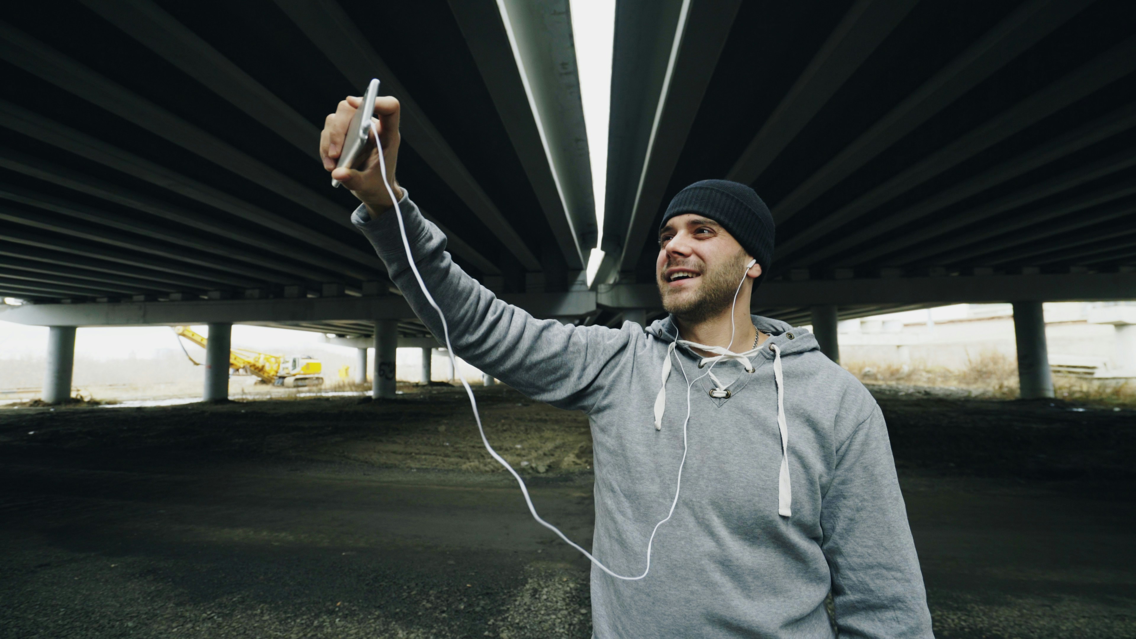 Man in beanie and hoodie taking a selfie