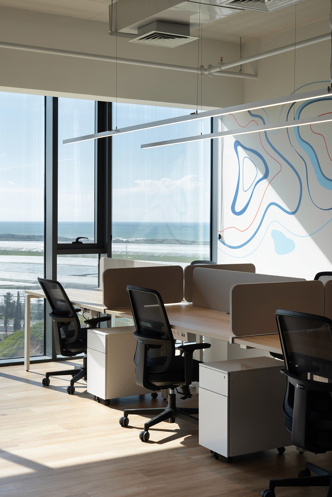 תכנון Open Space ארגונומי: עמדות עבודה עם מחיצות הפרדה נמוכות, הממוקמות תחת מערכות תקרה חשופות ומתוכננות לבידוד רעשים