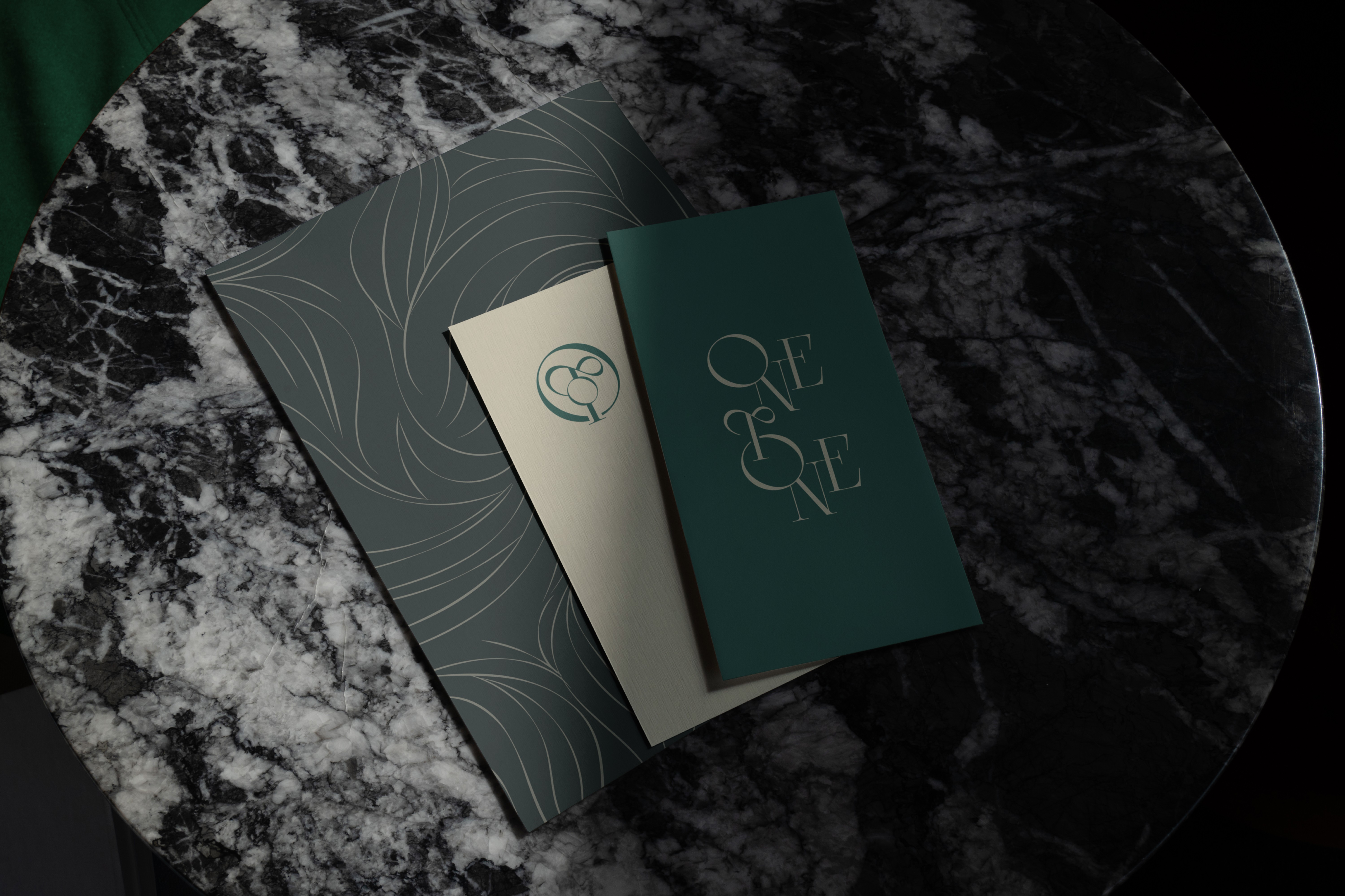Branded packaging and fashion collateral – Luxury booklets and marketing materials for Onetone, styled on a marble surface for an elevated aesthetic.