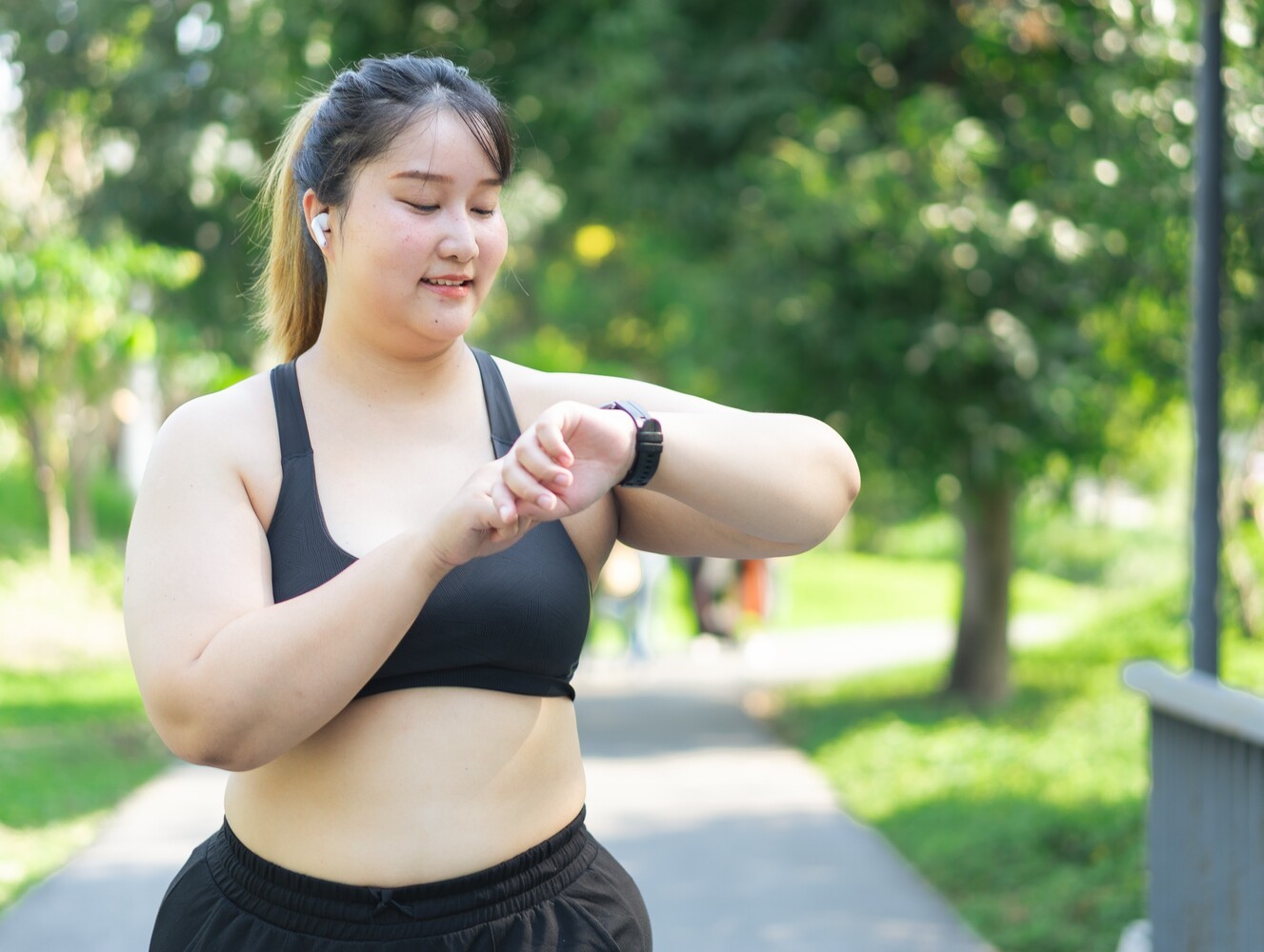 woman walking for exercise checking her fitness watch to see how many steps per day for weight loss she has done