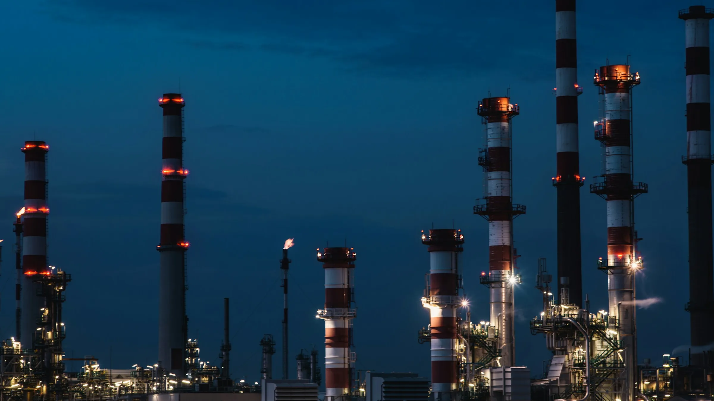 Refinery stacks lit up at night, where most grey hydrogen is made by steam methane reforming