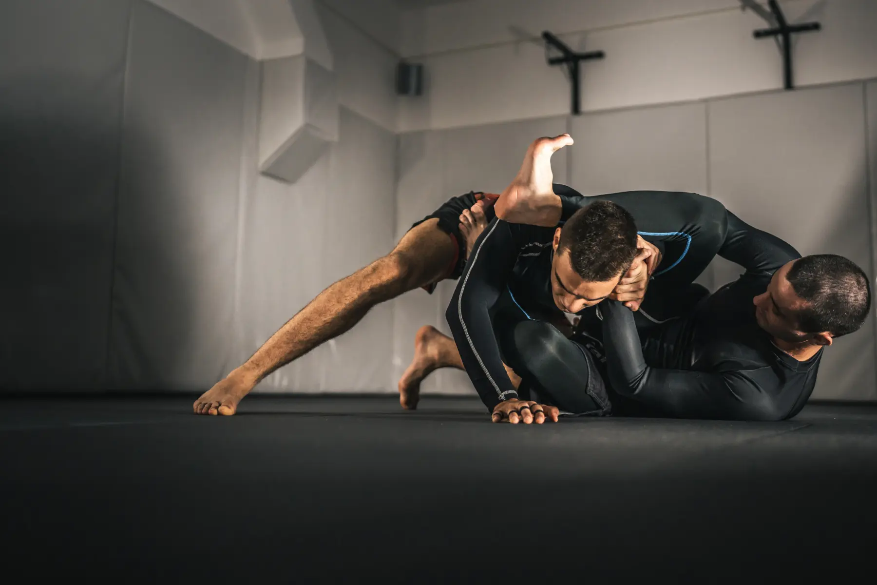 Two adults practicing Brazilian Jiu Jitsu grappling techniques during no-gi training