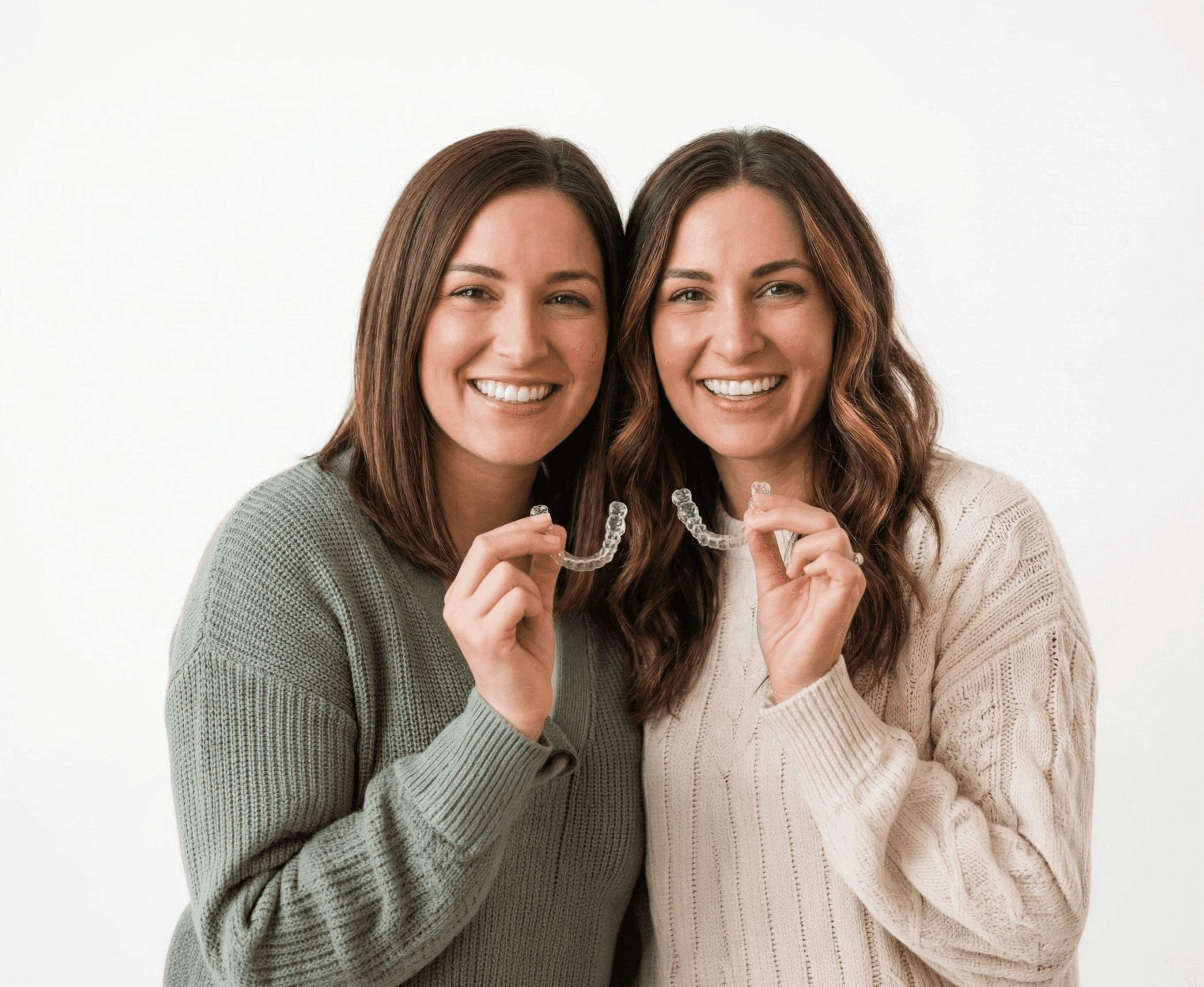 Invisalign in Dubai with a woman smiling confidently, holding her clear aligners, highlighting discreet and effective treatment.