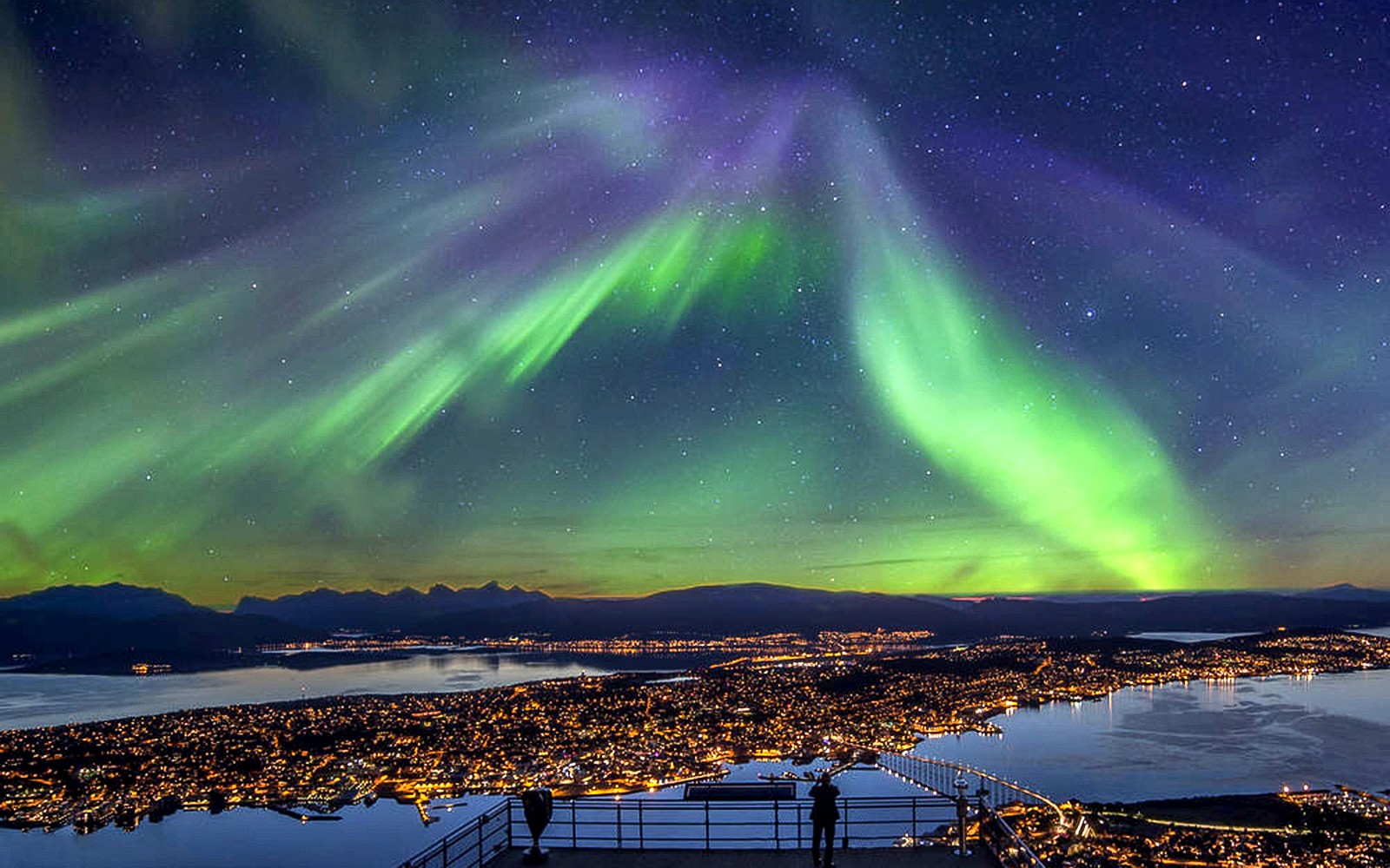 Northern Lights over cityscape during minibus tour in Norway.