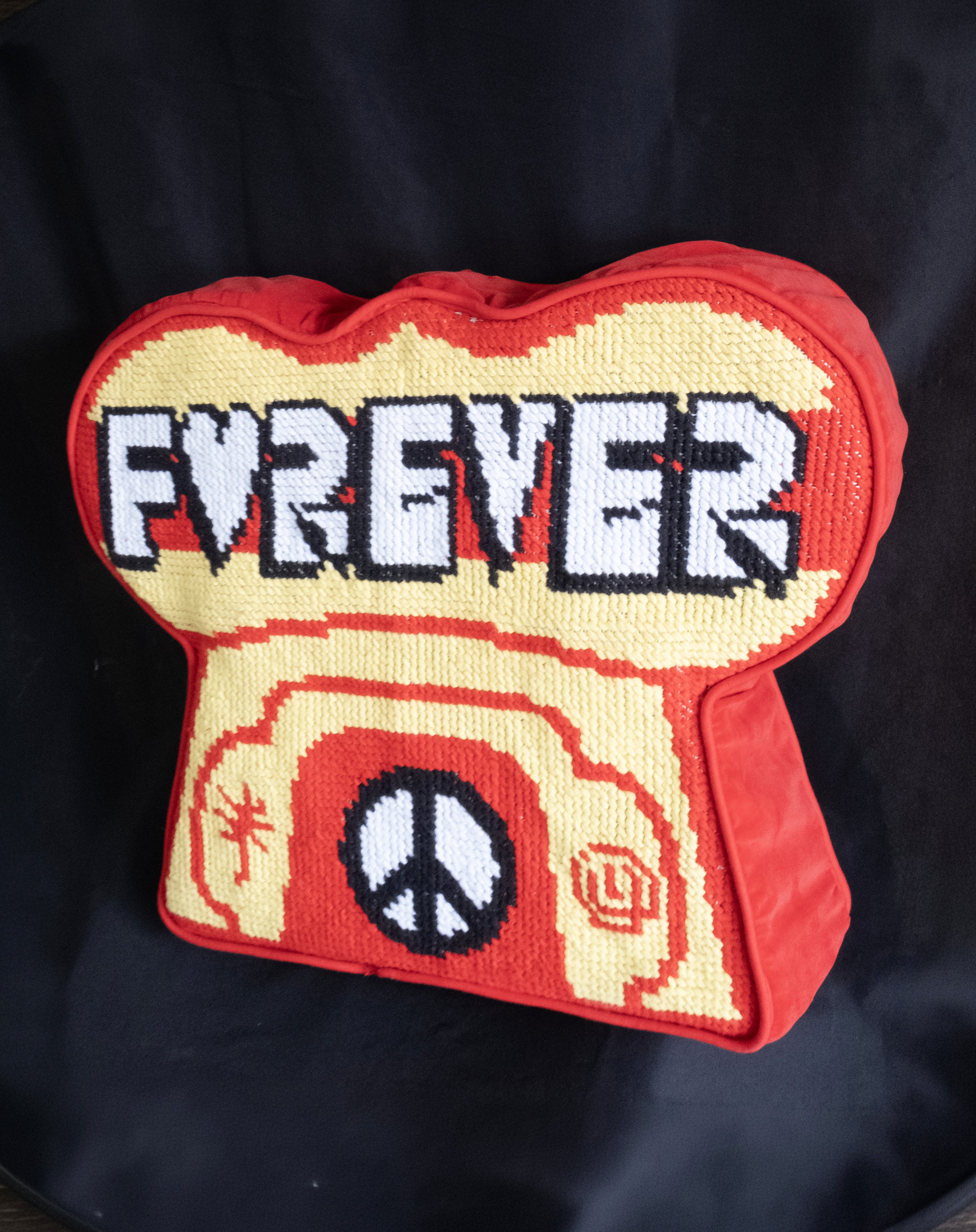 Red and yellow Forever cushion featuring graffiti-style lettering and peace symbols