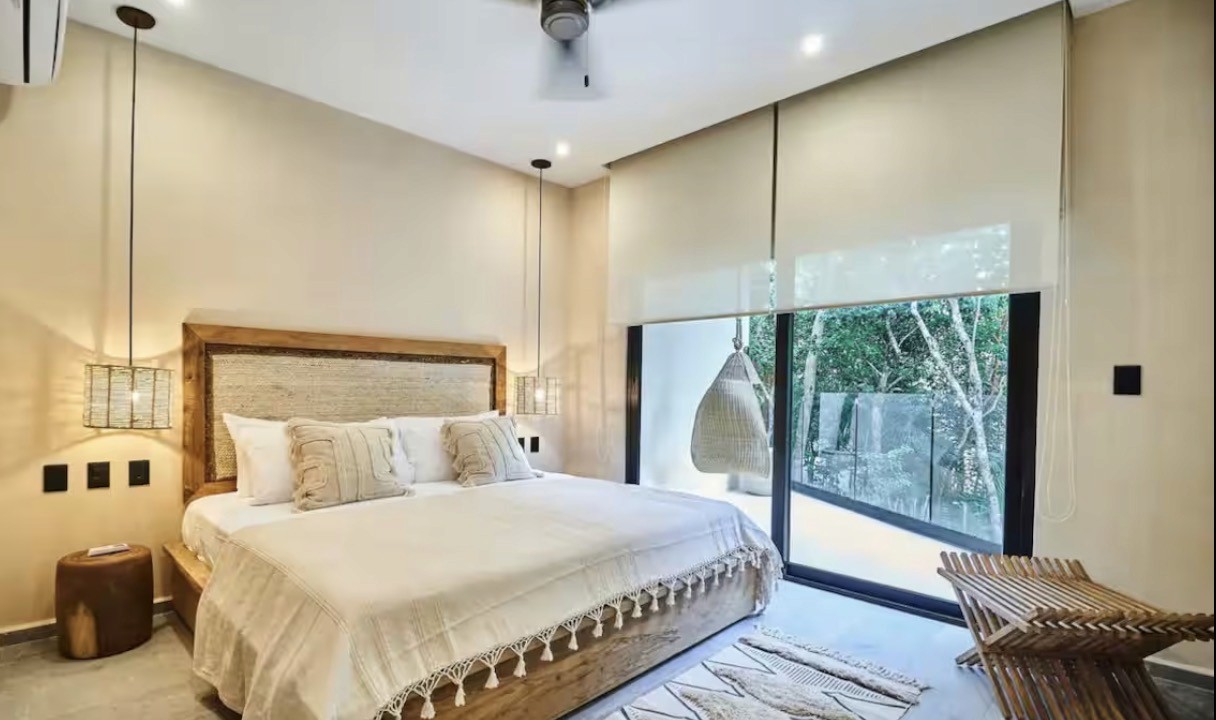 Group of hikers walking through a mountain meadow surrounded by pine trees and misty peaks.