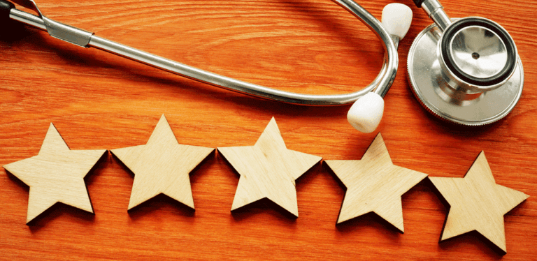 Five wooden stars and a stethoscope on a table, representing healthcare ratings.