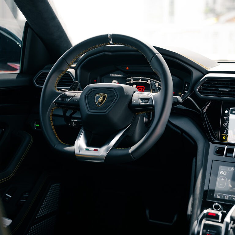 Driver's view Lamborghini Urus S steering wheel, digital dashboard, performance SUV rental Miami.