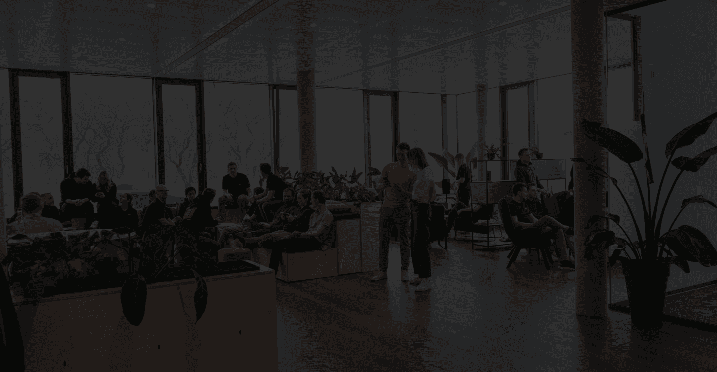 Eine Szene in einer Bürolounge in der viele Menschen sitzen sich unterhalten und an einer Konsole spielen