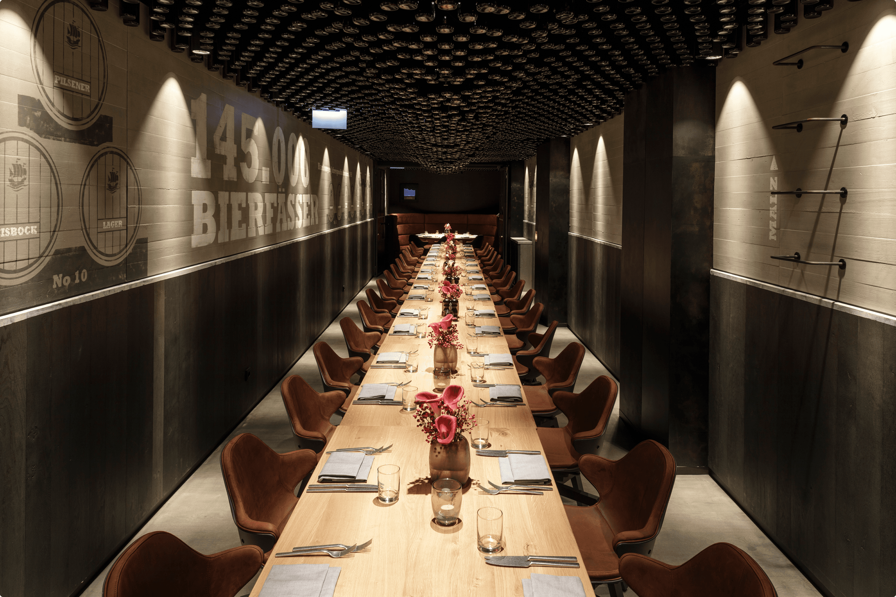 Long wooden table set for a meal with brown chairs.