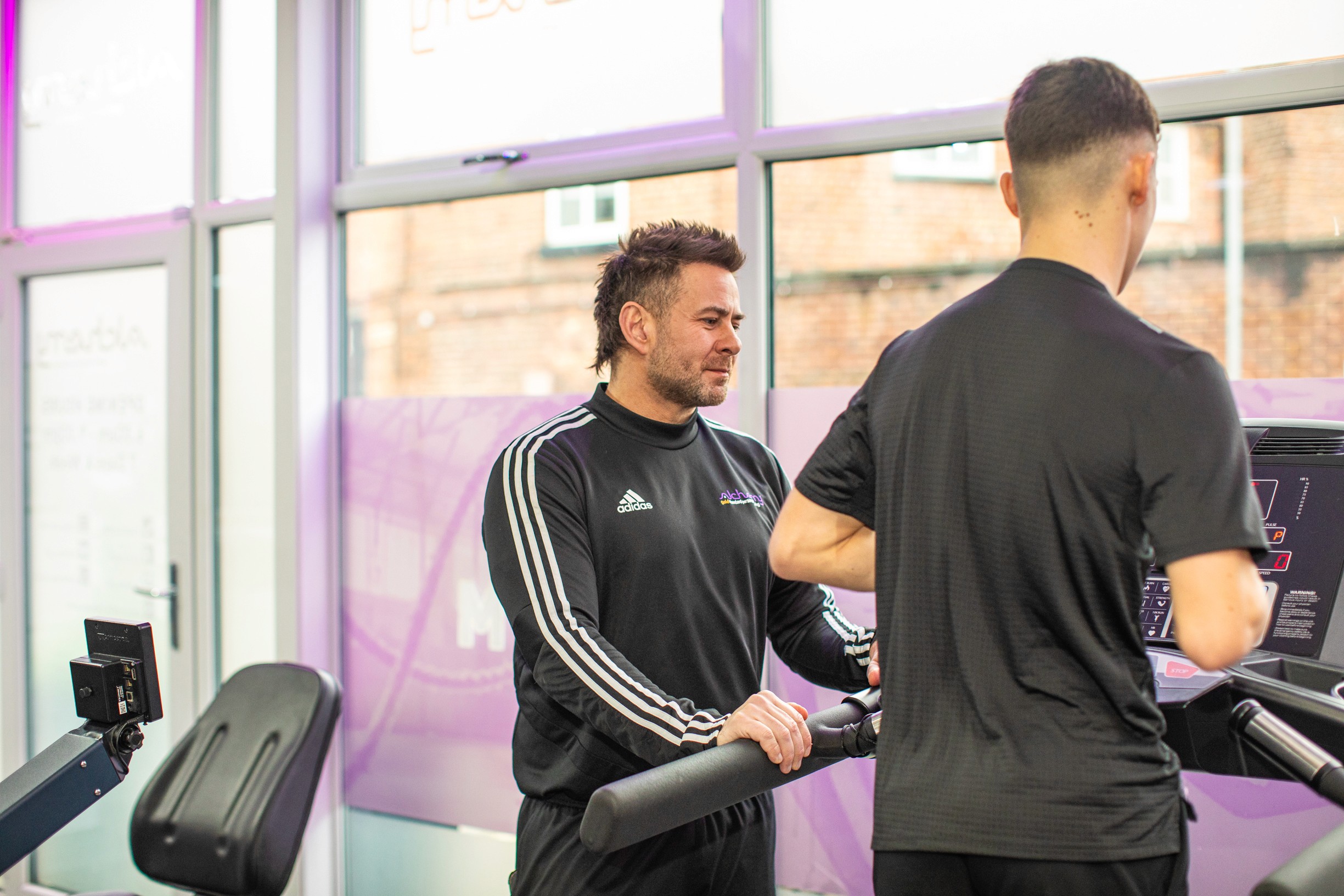 A personal coach is smiling with his arms crossed, wearing a black 