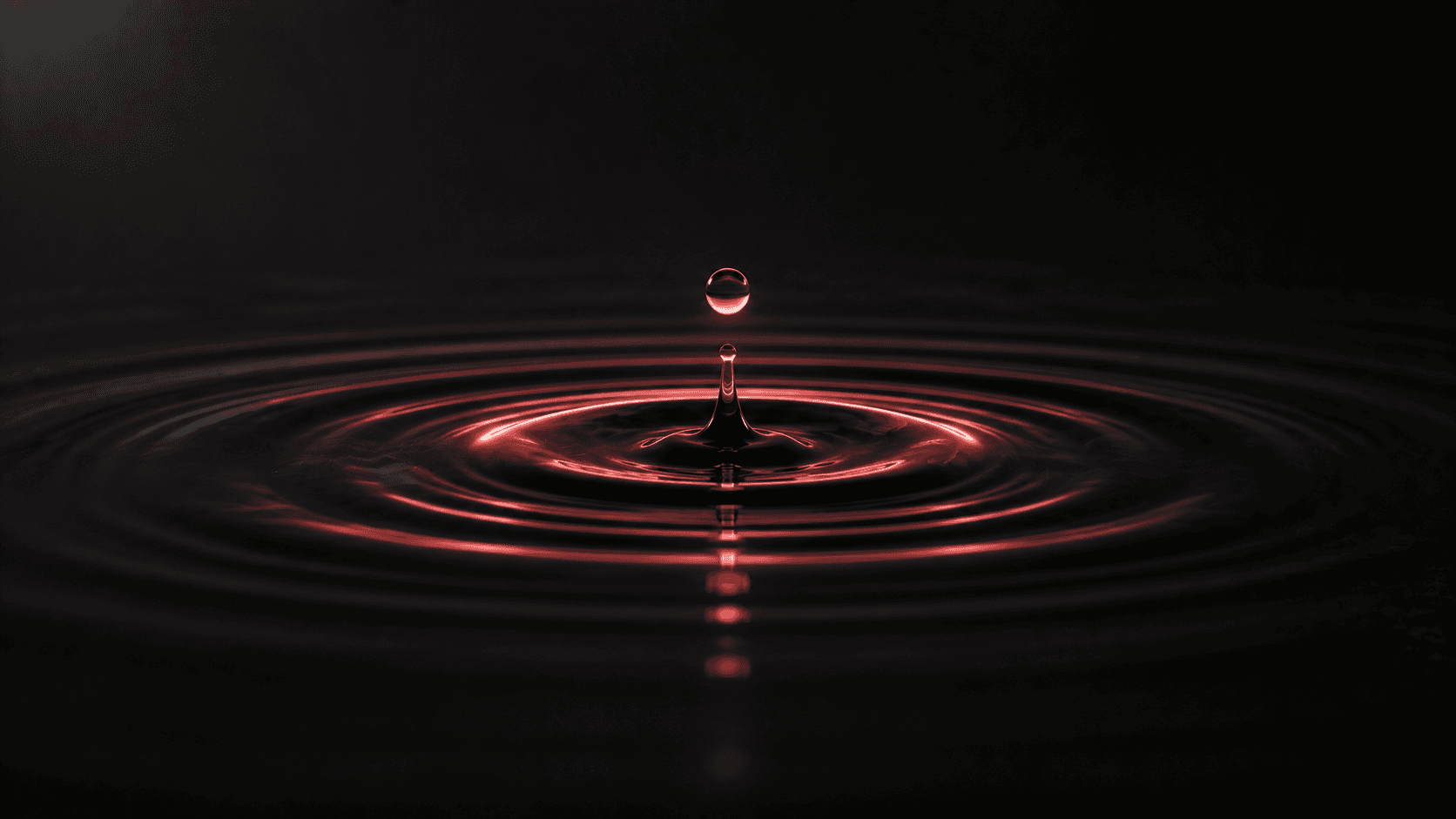 A single coral-red ripple expanding on a dark still surface, representing a microinteraction adding subtle delight.