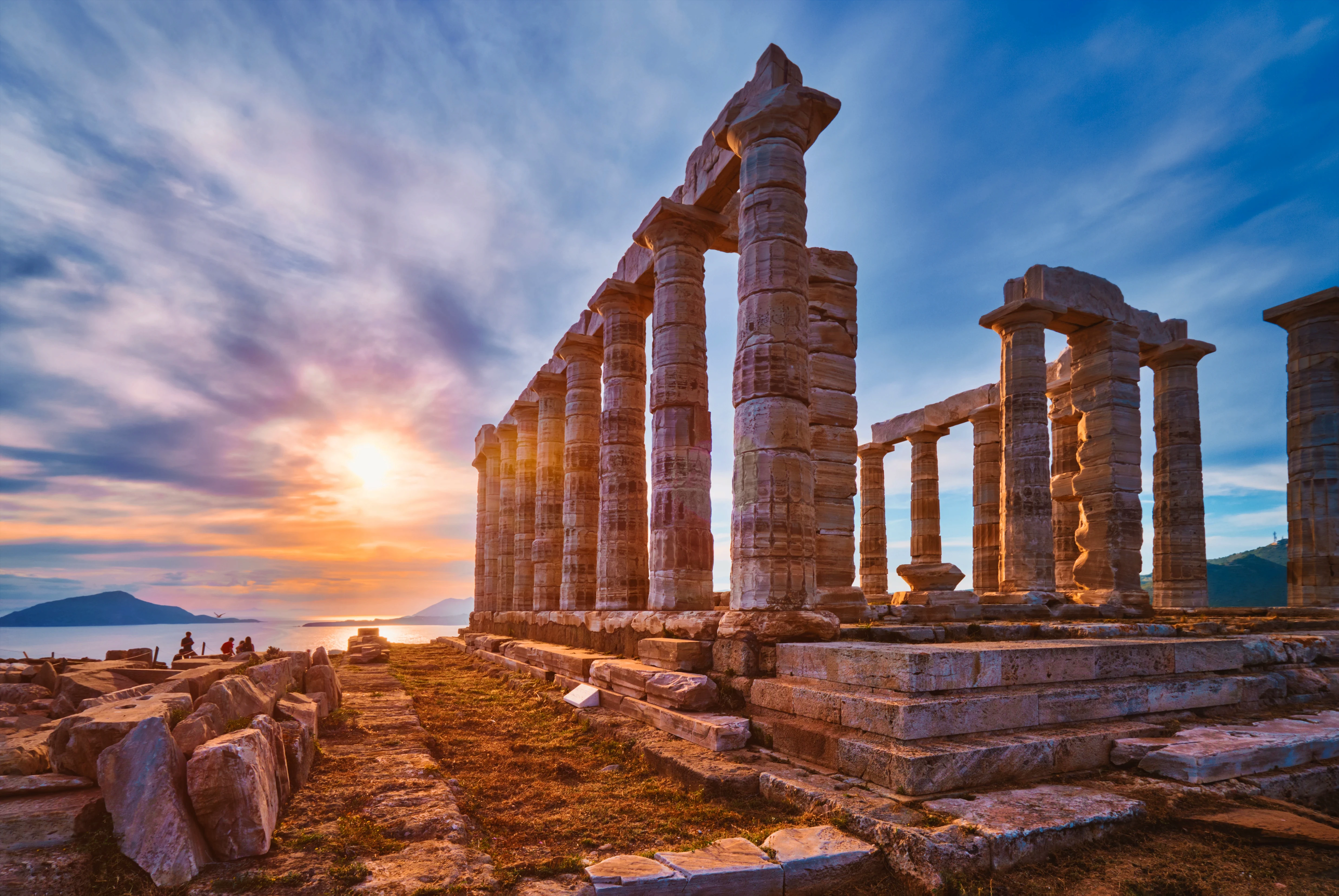 The ancient ruins of the Temple of Poseidon at Cape Sounio, Greece, during a dramatic sunset.