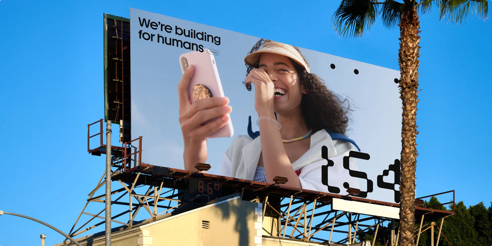 A large billboard featuring a woman in a hat, smiling, against a clear blue sky.