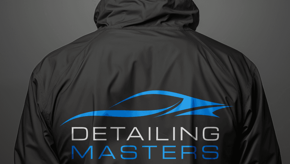 Detailing Masters logo across the back of a dark colored windbreaker style jacket worn by a male model