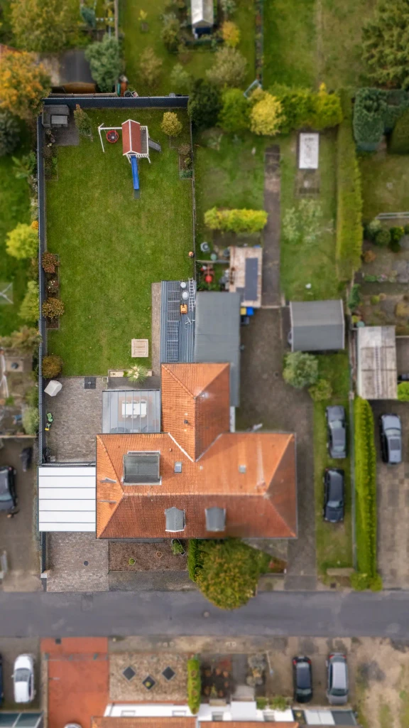 Drohnenaufnahme eines Einfamilienhauses mit großem Garten und rotem Dach in Gronau – Immobilie von Westfalen Wohnen.