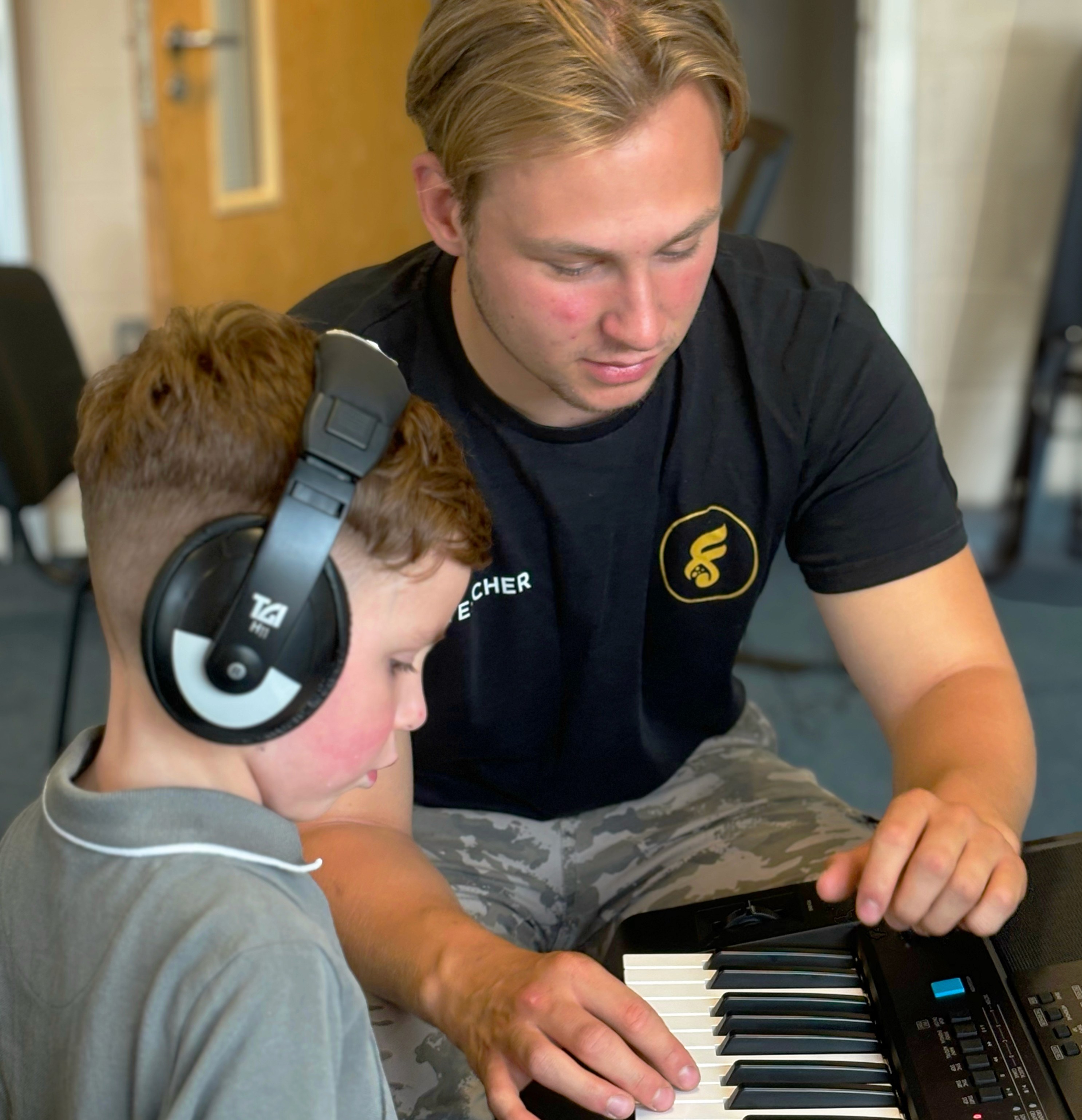 Teacher with student learning the keys on a keyboard