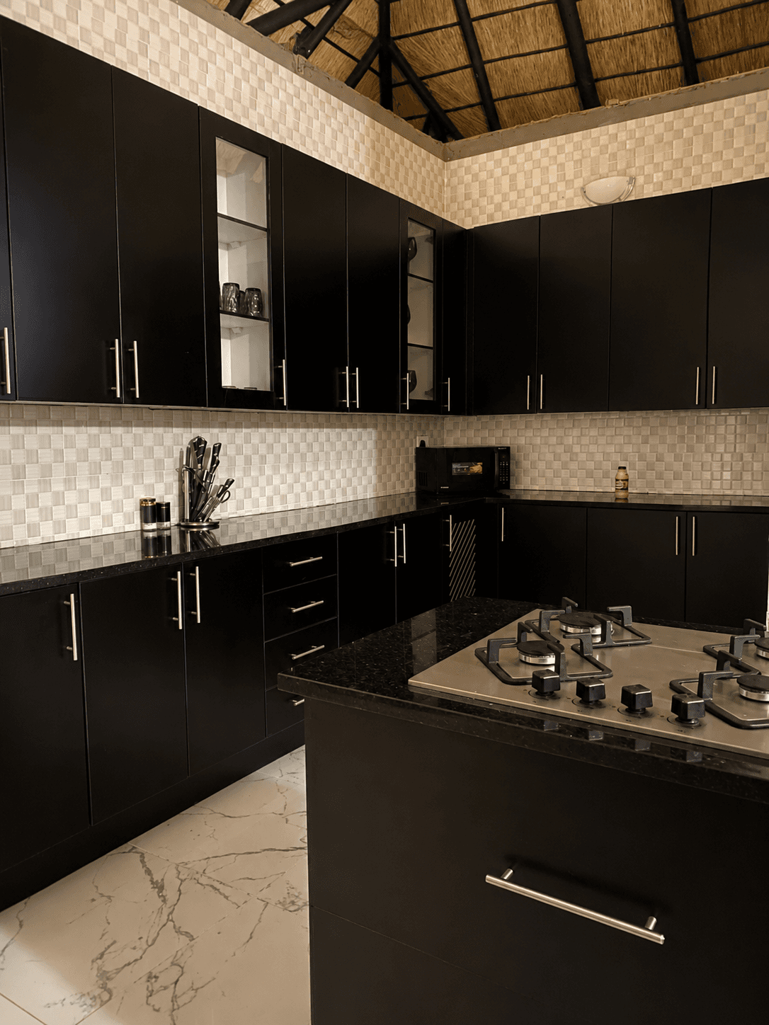Black kitchen cabinetry with gas hob and tiled walls