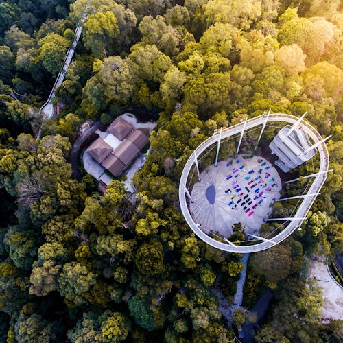 俯瞰森林，一座圆形结构，五彩斑斓的垫子排列在平台上，周围有建筑物。