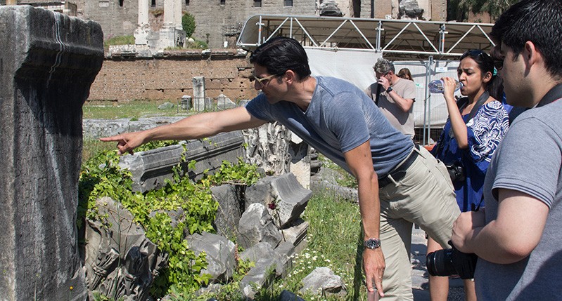 a man pointing at a stone
