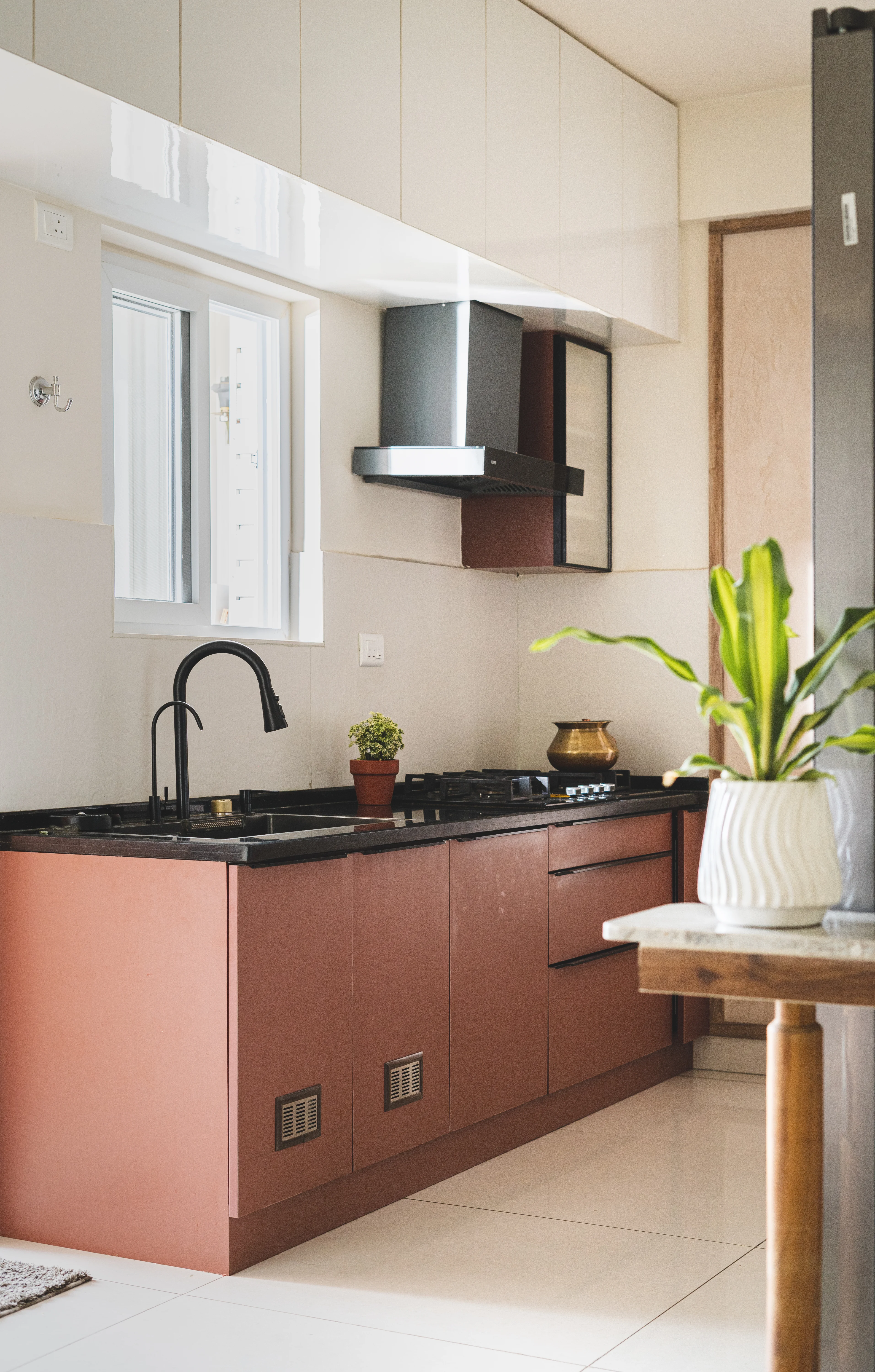 A modern kitchen featuring a curved sink, sleek counter, and stylish cabinets, designed for South Indian homes.