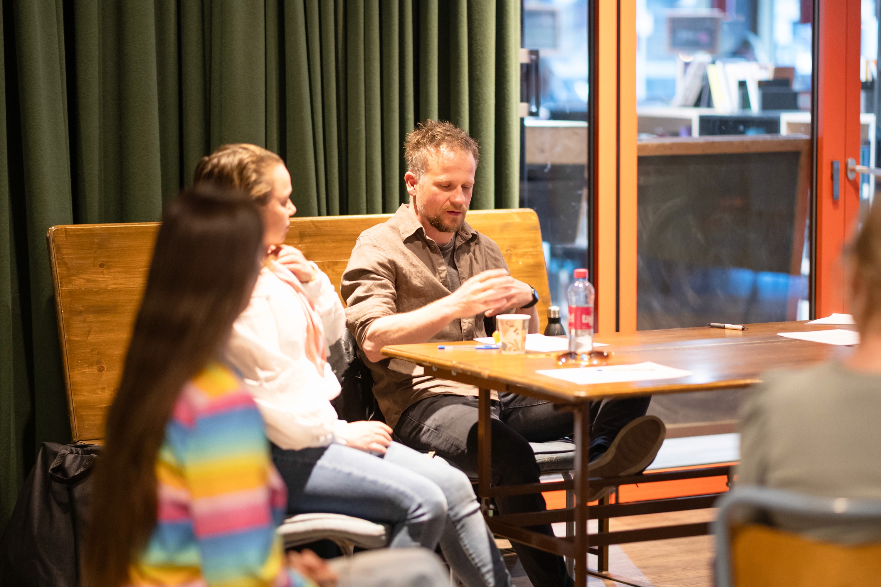 People sitting around a table listing to a person talking