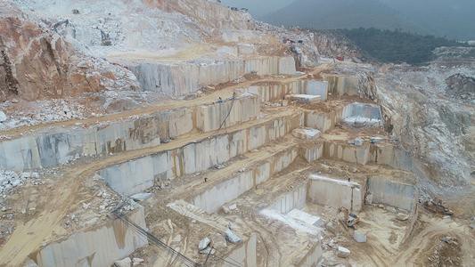 Panoramic view of a stone quarry landscape, displaying multiple terraced levels and showcasing the vast scale of stone extraction operations.