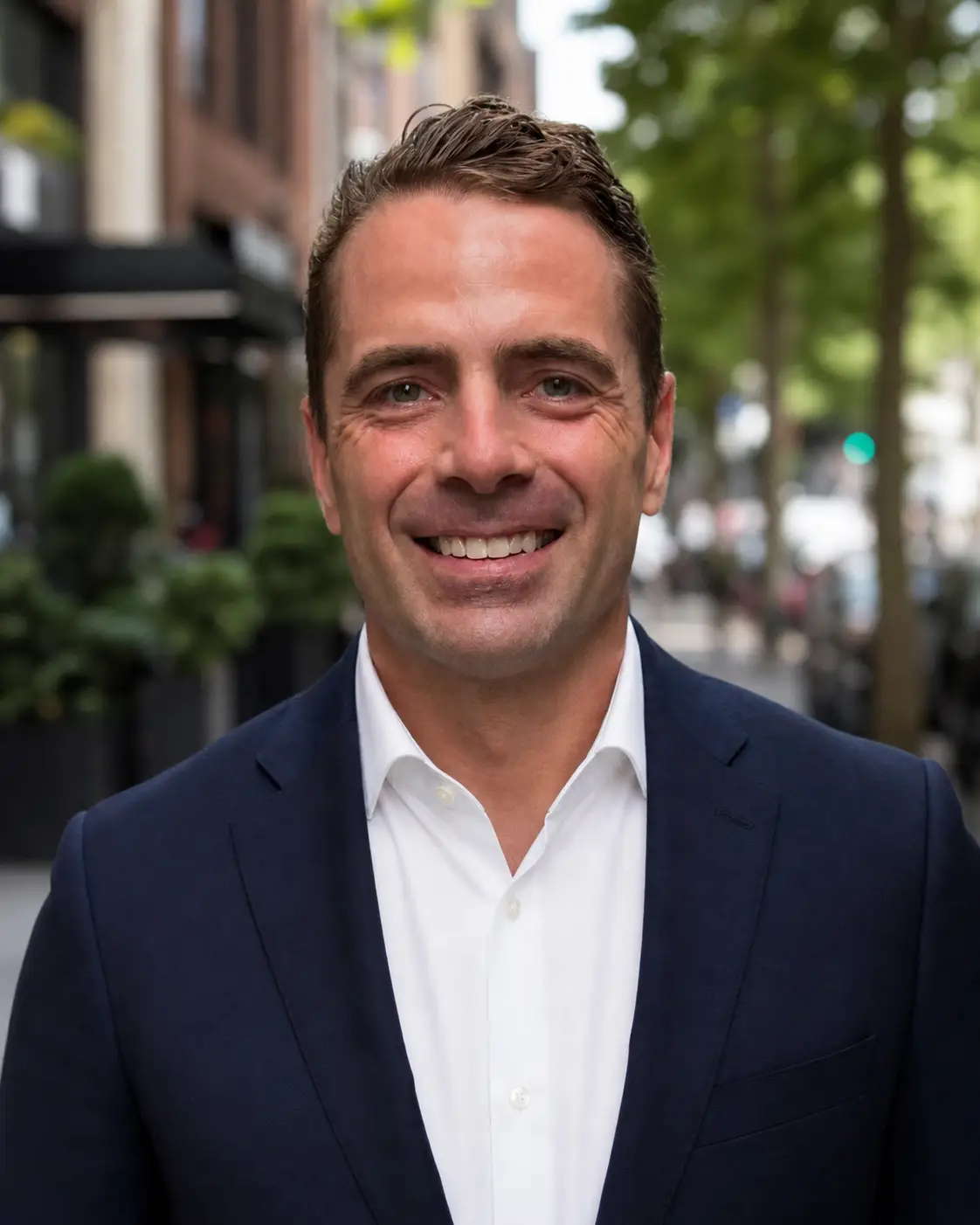 Andrew Borchini of BRN Partners, a white man with wavy brown hair wearing a white button down shirt and a navy blazer 