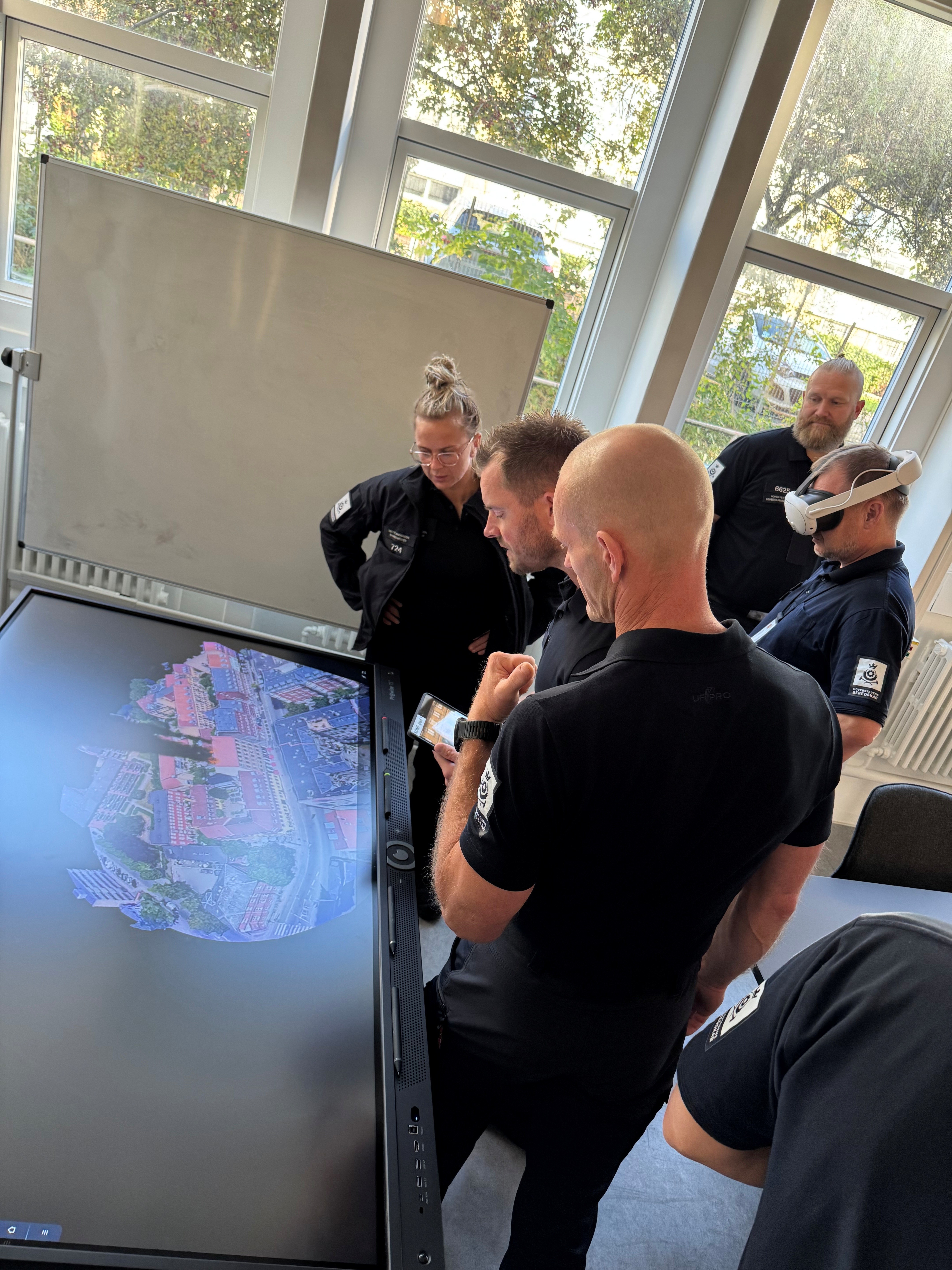 A group of people form Copenhagen fire department watching a scenarion on a screen