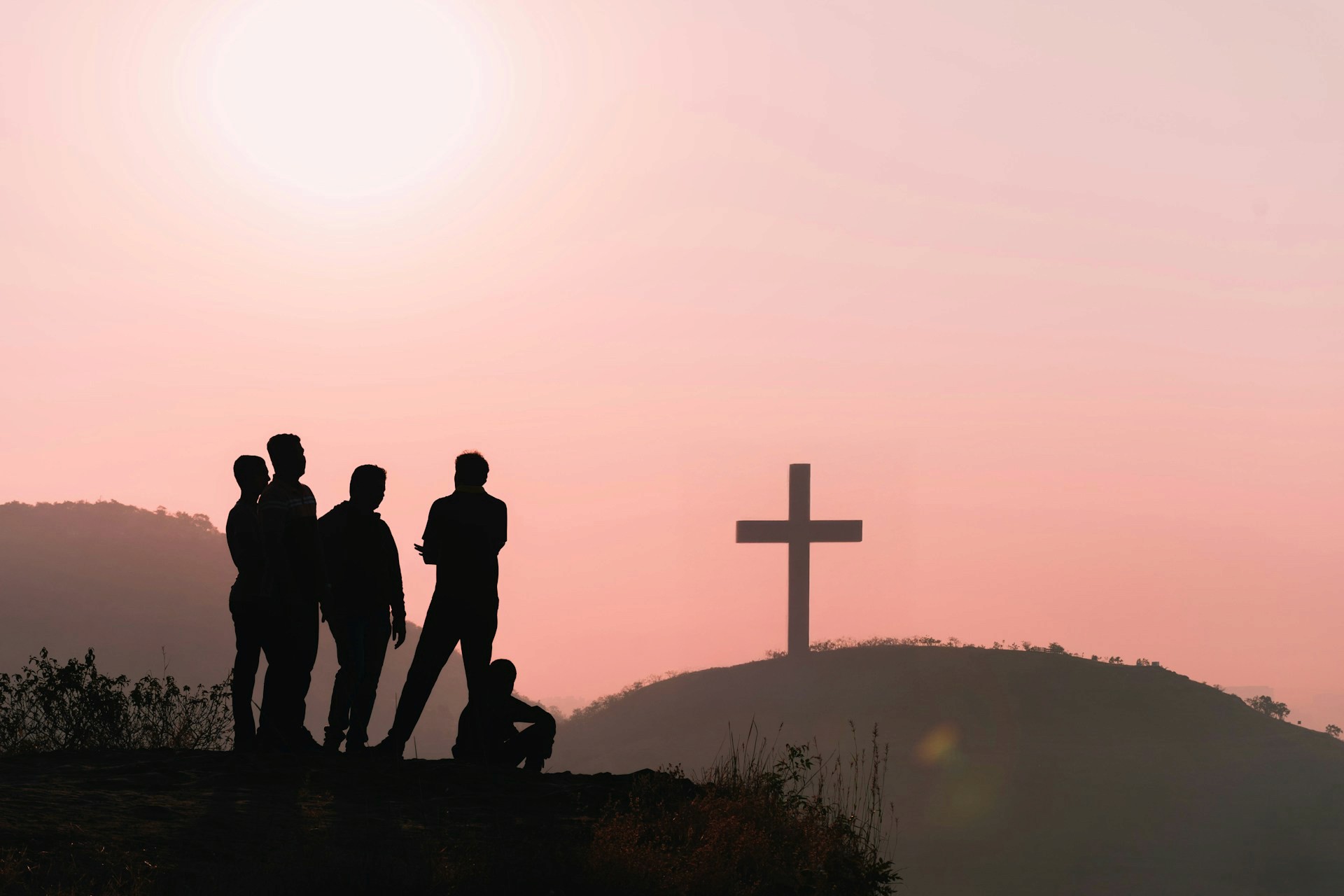 Un groupe de personnes avec une croix chrétienne au loin