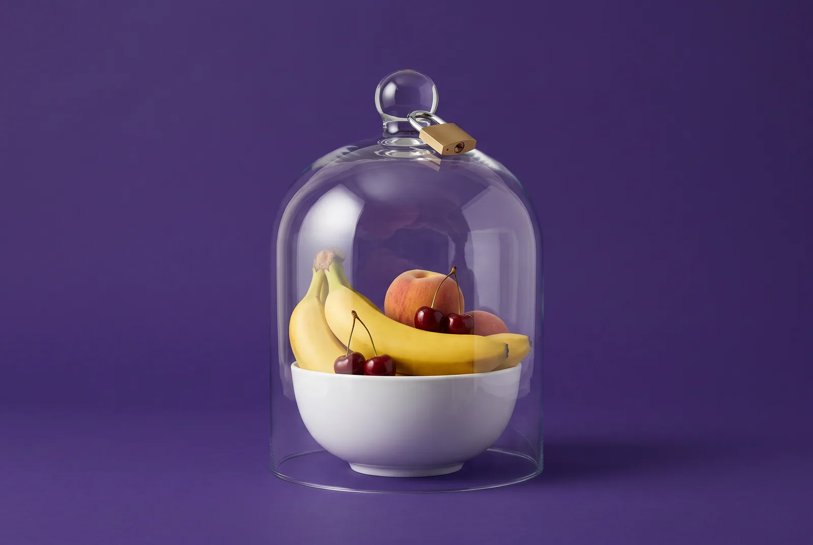 Glass bell jar with a padlock on its knob covering a whole bowl of bananas, peaches and cherries on a deep purple backdrop, a metaphor for forcing SafeSearch on a router