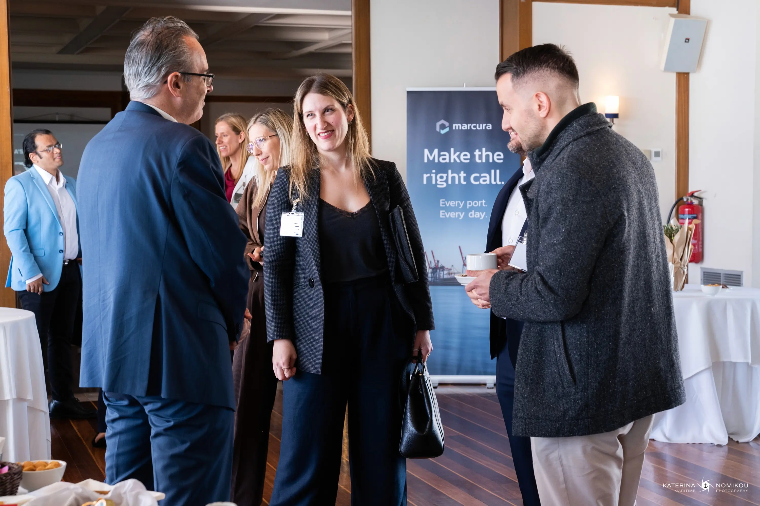 Three professionals engaged in conversation at a gathering, with a backdrop of a business setting.