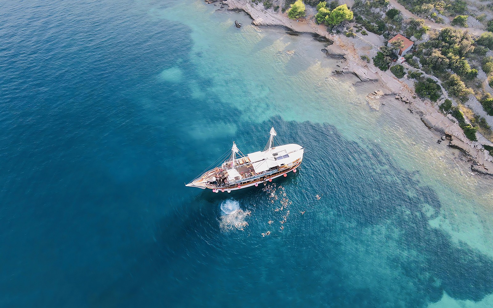 Boat party at Blue Lagoon, Split, Croatia with people swimming nearby.