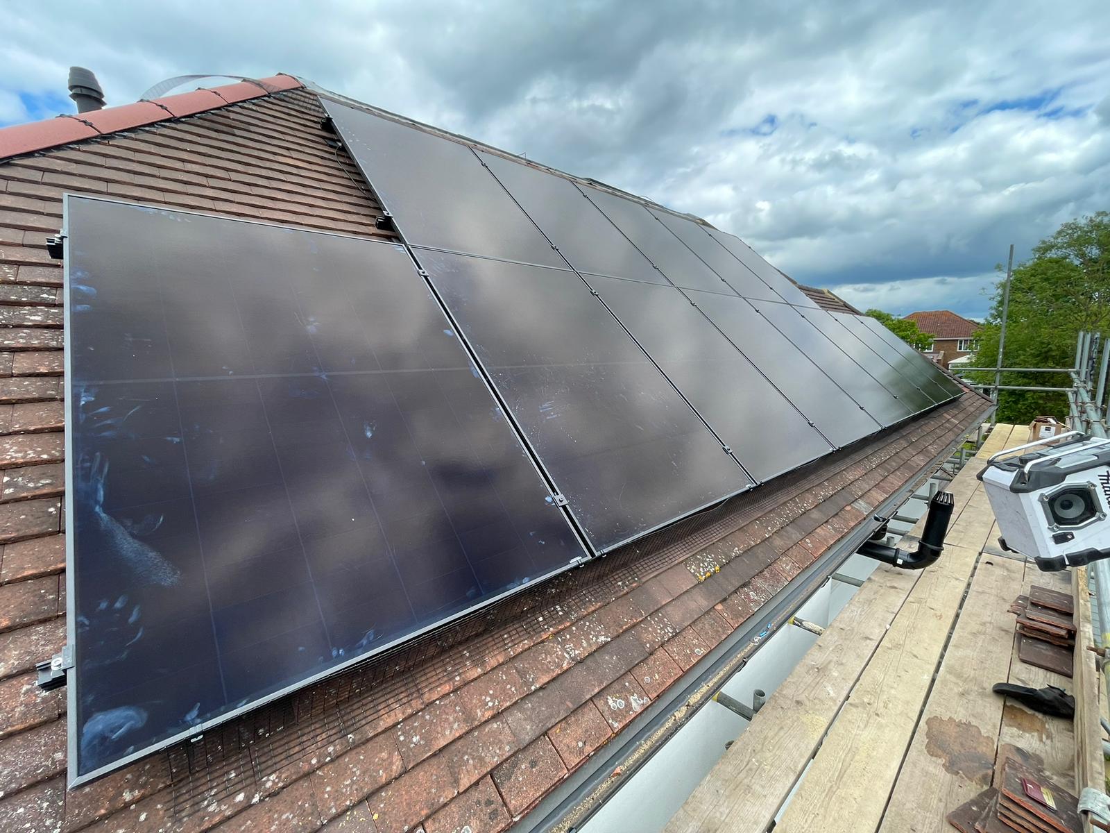 Black solar panels covering the tiled roof at Matt and Ali's home, with scaffolding still in place