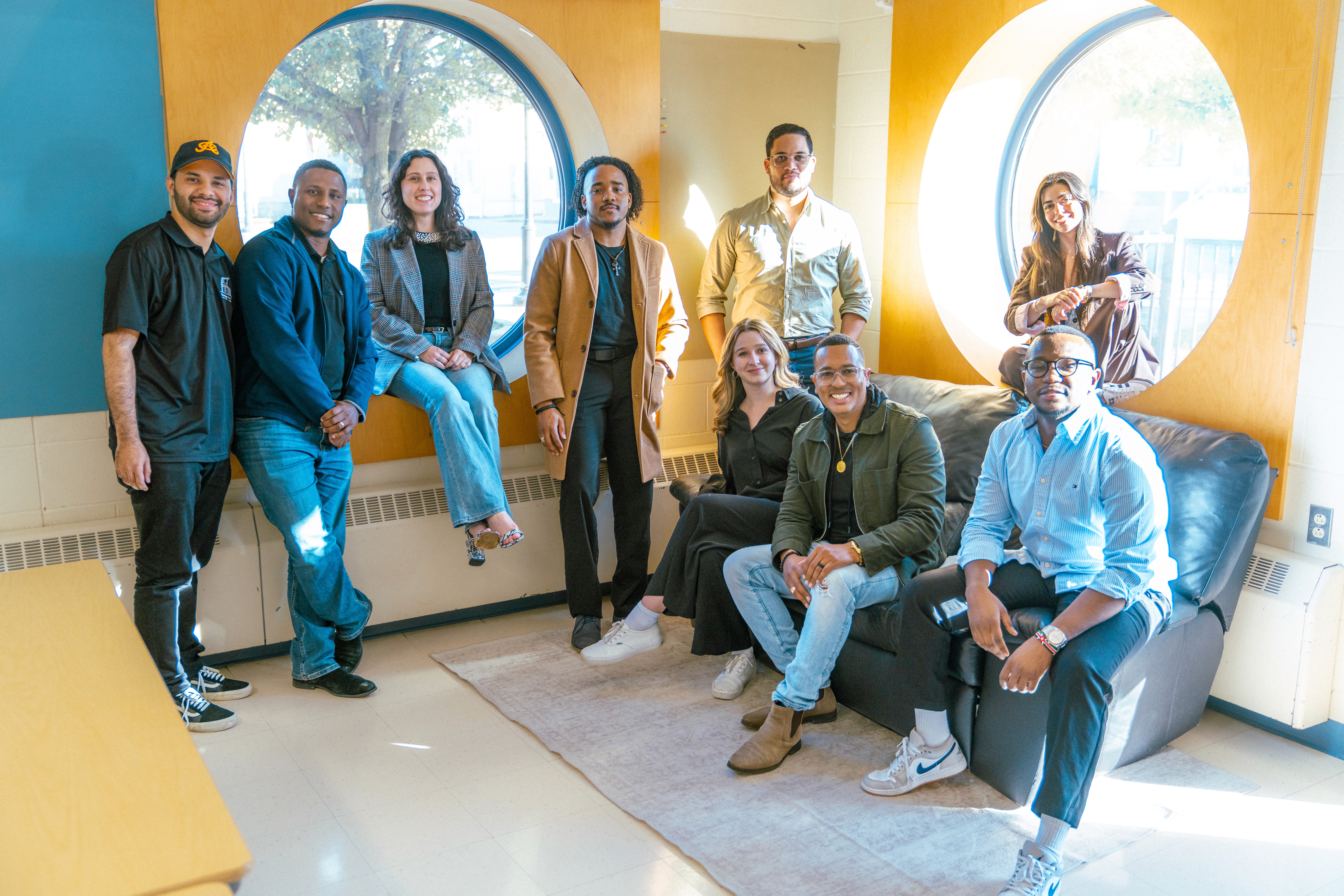 The Flow Design Architects team gathered in a sunlit room in front of two large circular windows.