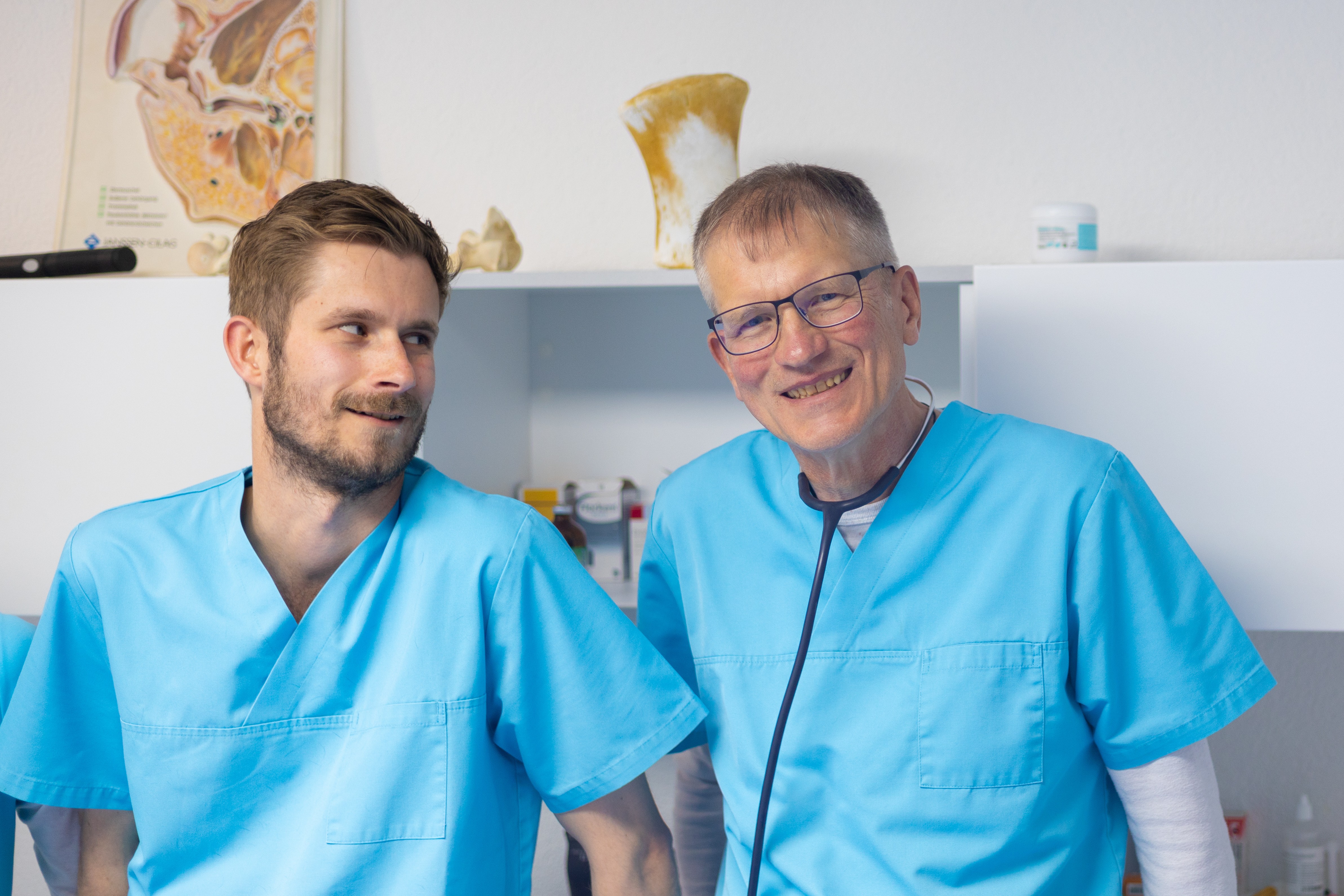 Zwei lächelnde Tierärzte in blauer Arbeitskleidung in einer Tierarztpraxis.