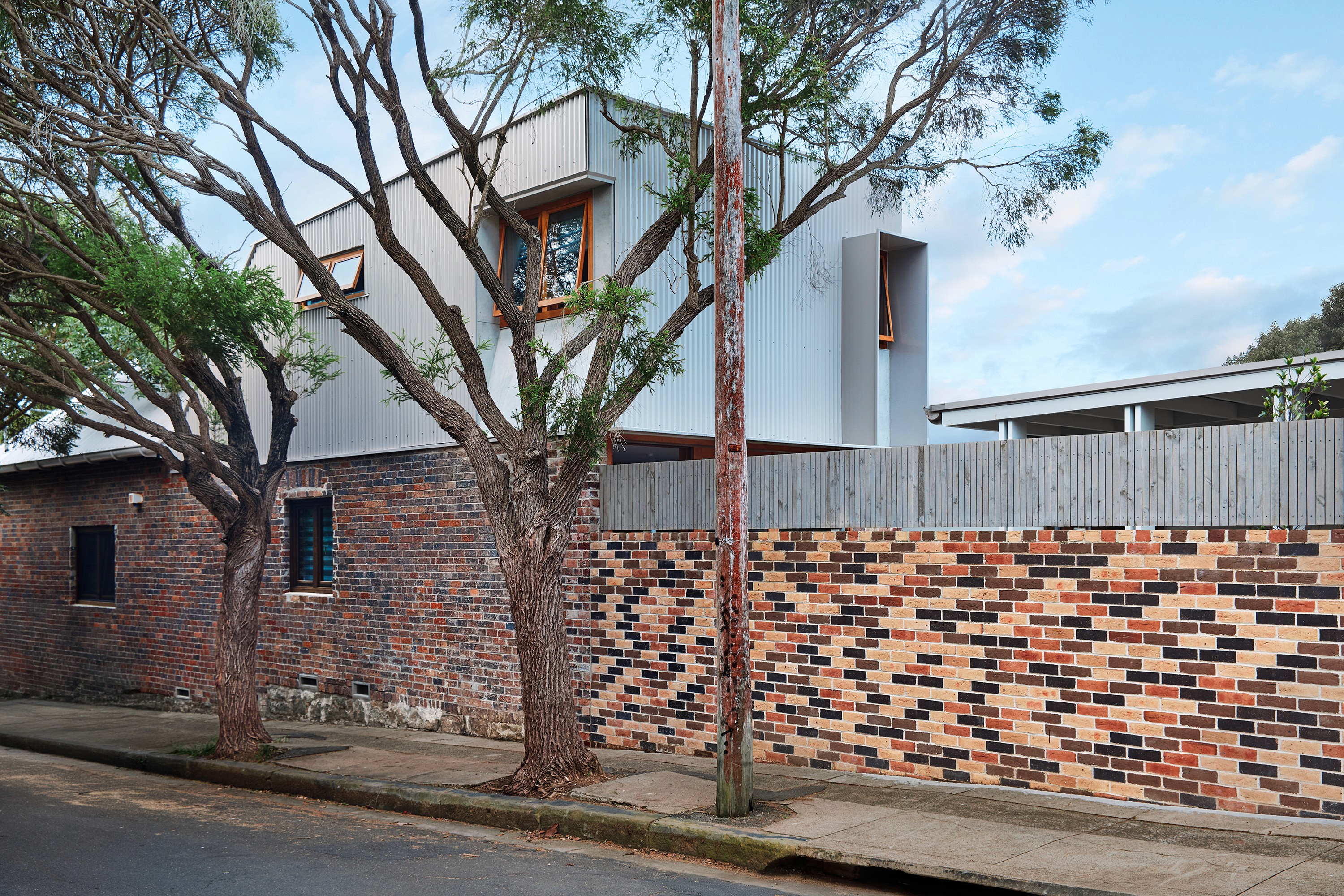 Minimalist pavilion with a perforated roof casting shadows on the white courtyard below.