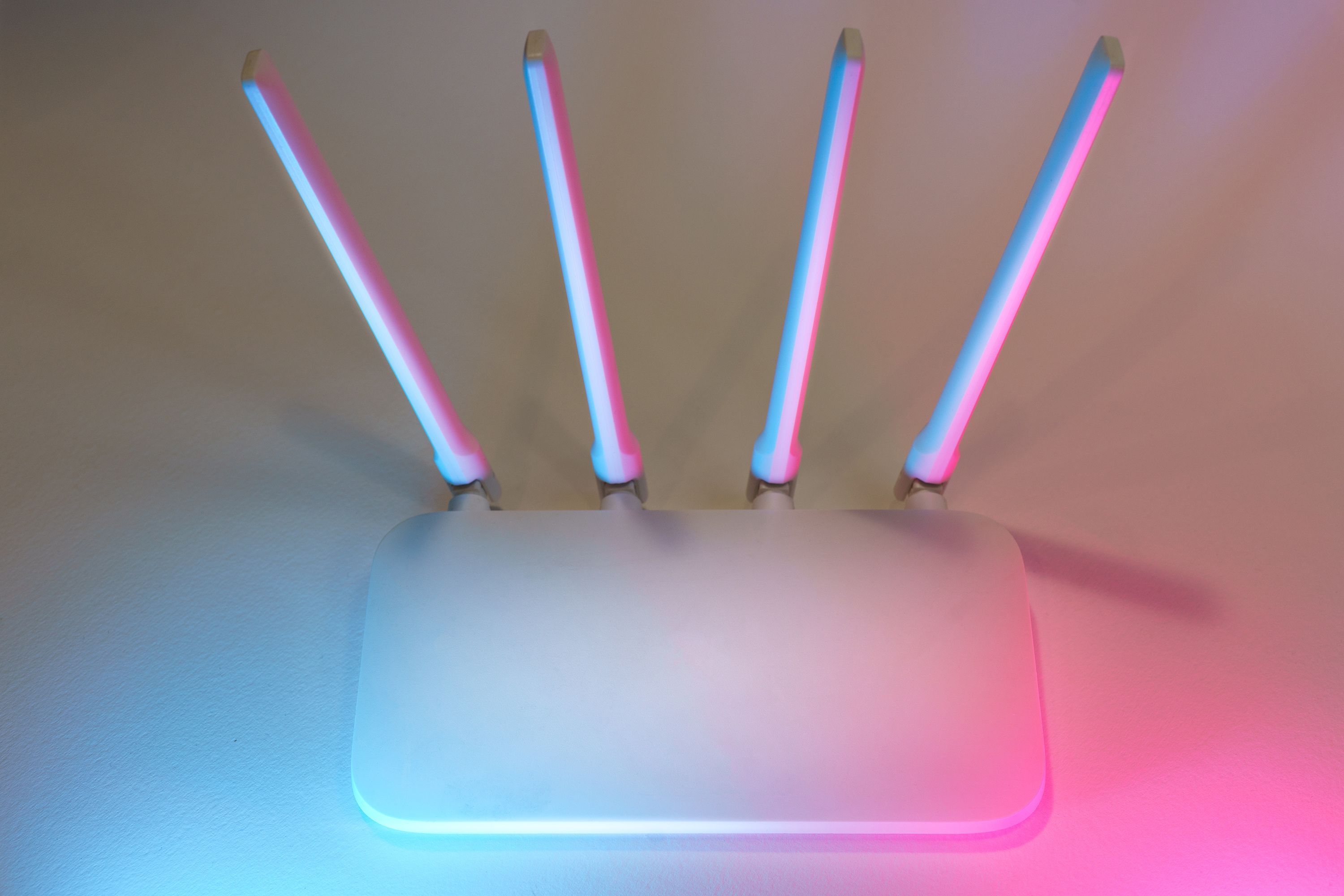 sleek-white-wireless-router-with-four-antennas-emitting-soft-blue-and-pink-light - jakub-zerdzicki (pexels)