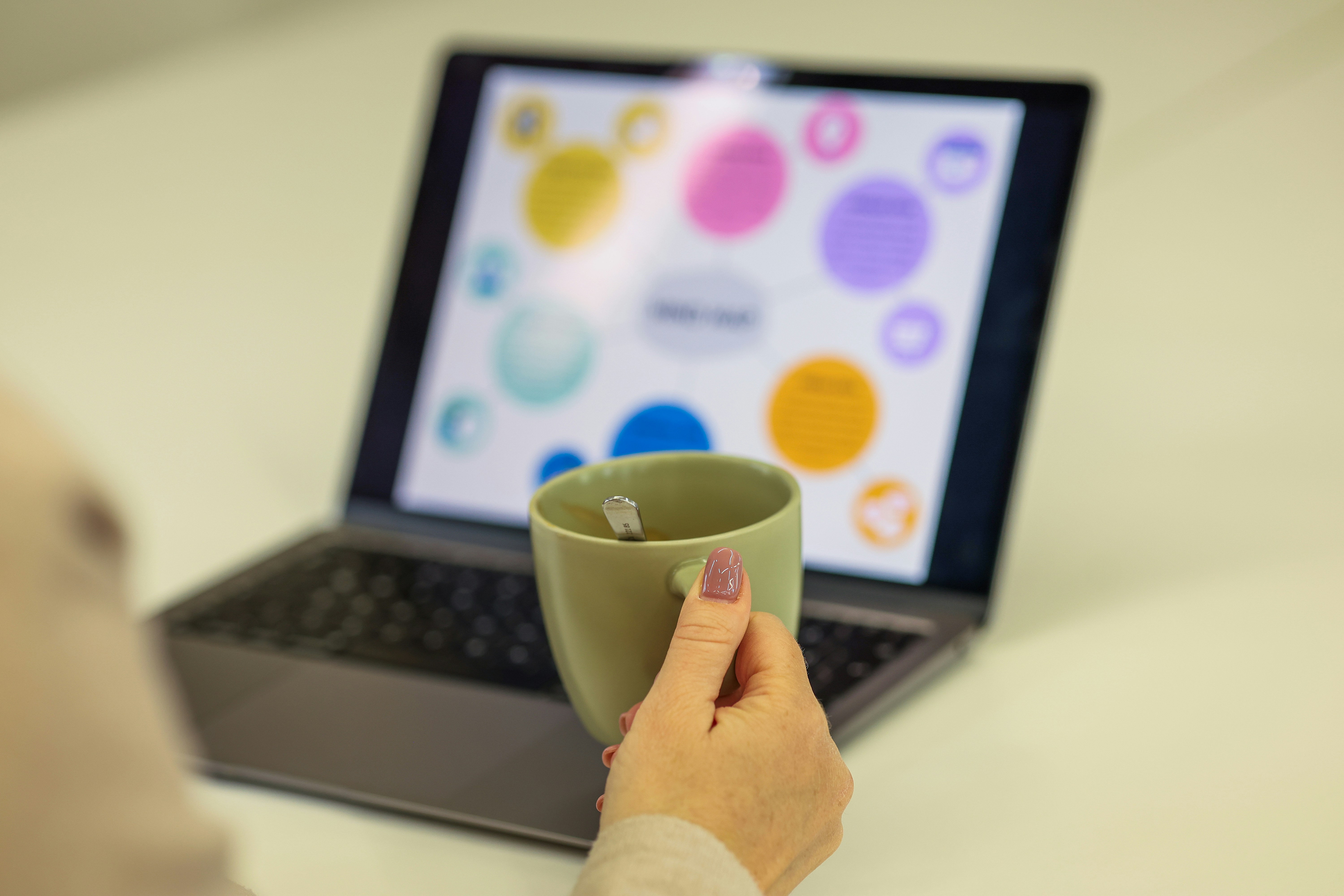 Colorful laptop interface with a hand holding a coffee mug representing a creative environment