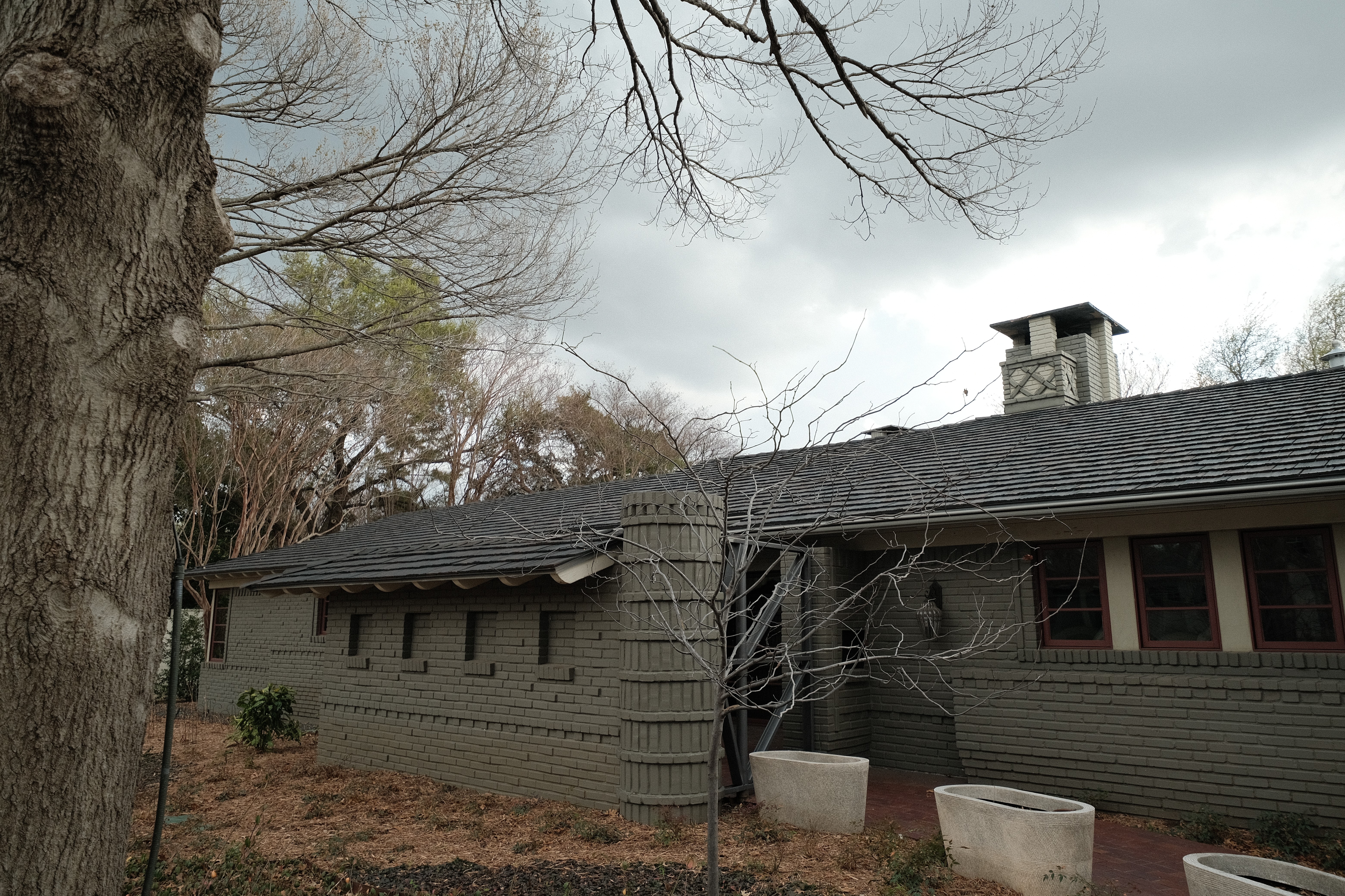 Side elevation of the Kessler Park ranch with the new Brava synthetic shake roofline reading against mature trees