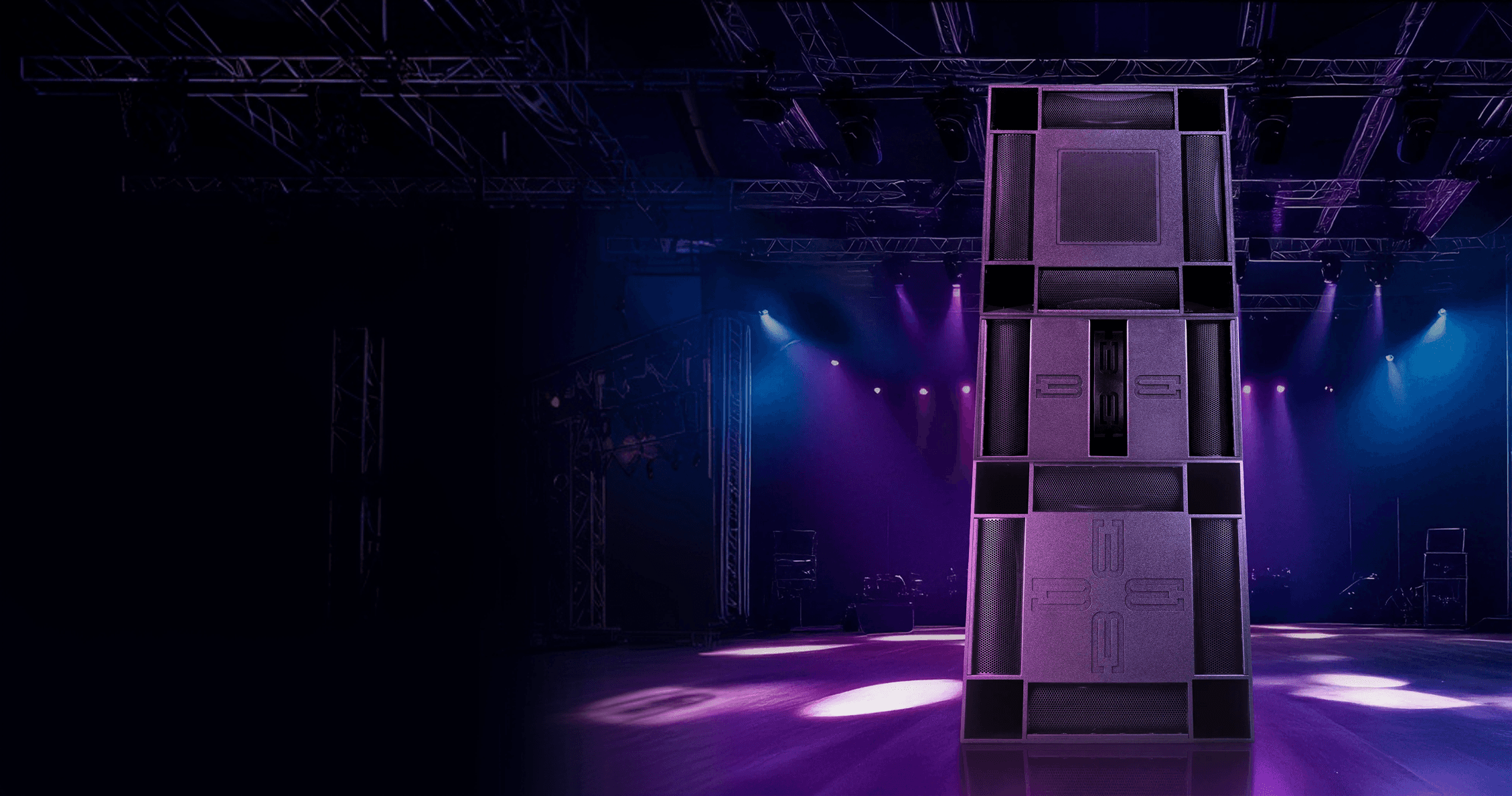 Modular speaker system on a stage with purple and blue lights.