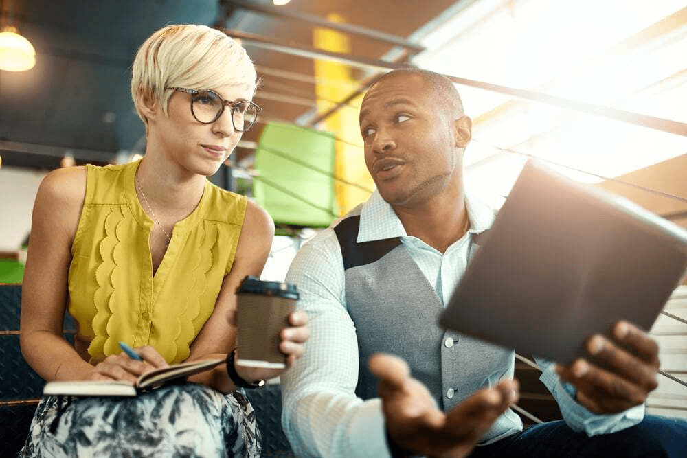 Two people looking at a phone in an lively area.