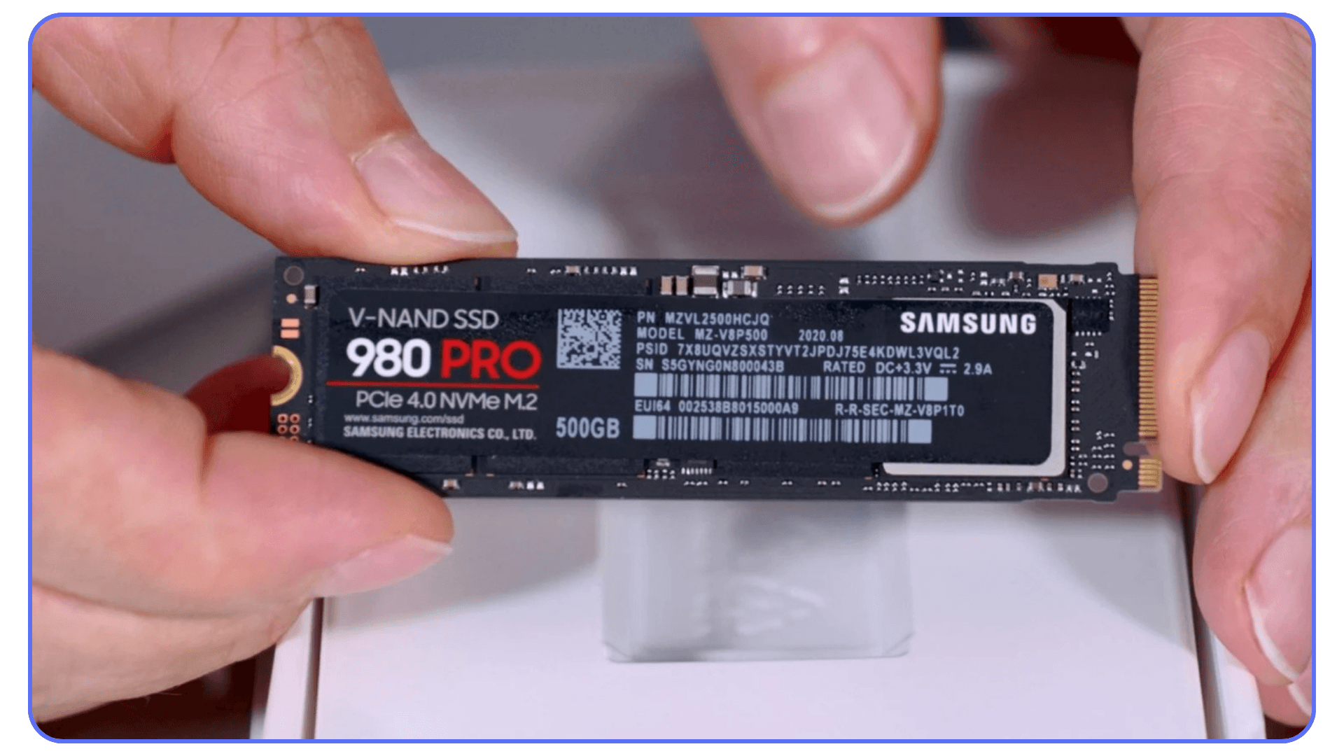 A person holding a Samsung 980 PRO NVMe SSD with 500GB capacity, featuring the drive's branding and model details.