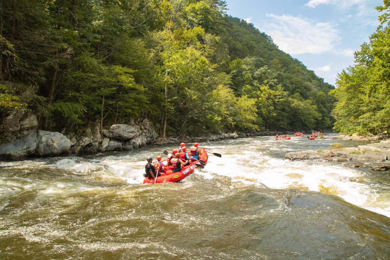 A group of rafters paddles through river whitecaps in the Great Smoky Mountains.