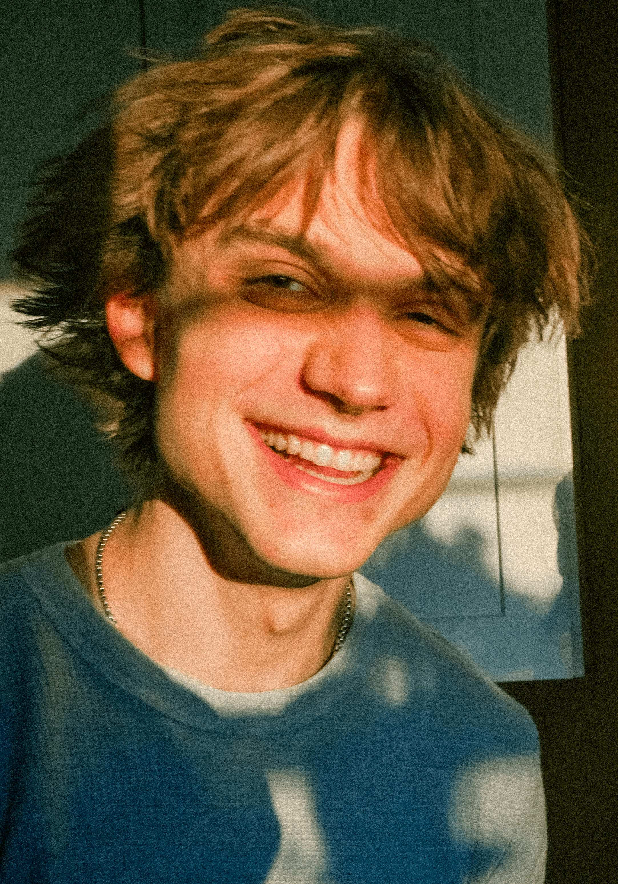 A thoughtful young person with dark hair gazes to the side, captured in soft black and white lighting.